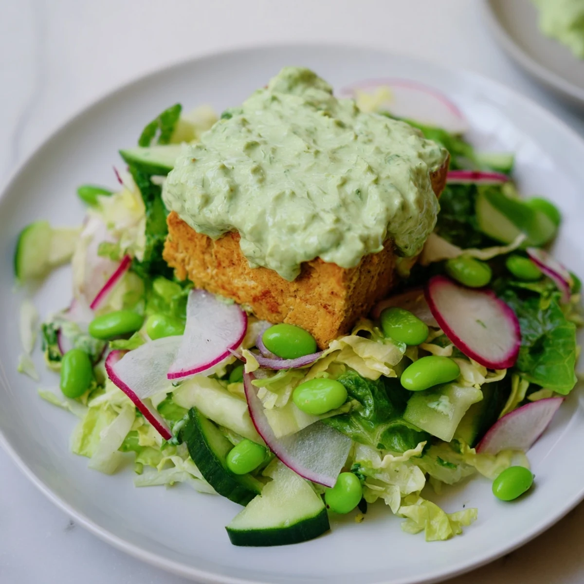 Golden-brown baked tofu cubes sit atop a crisp mix of romaine, shredded cabbage, cucumber, and creamy avocado chunks.