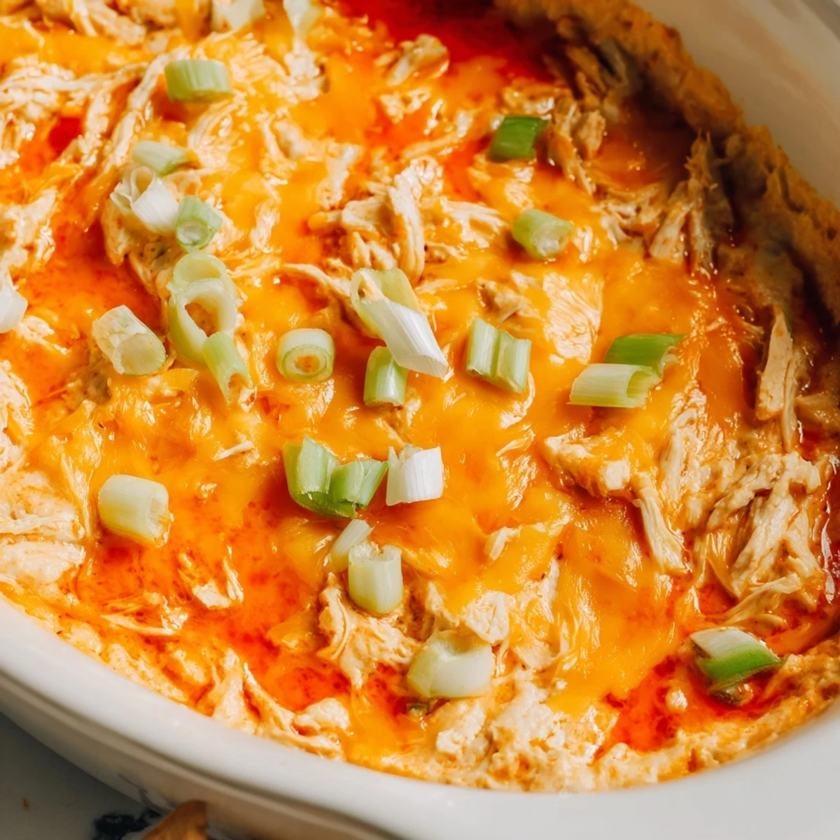Creamy, spicy Touchdown Buffalo Chicken Dip is garnished with green onions and served with crisp celery sticks and tortilla chips.