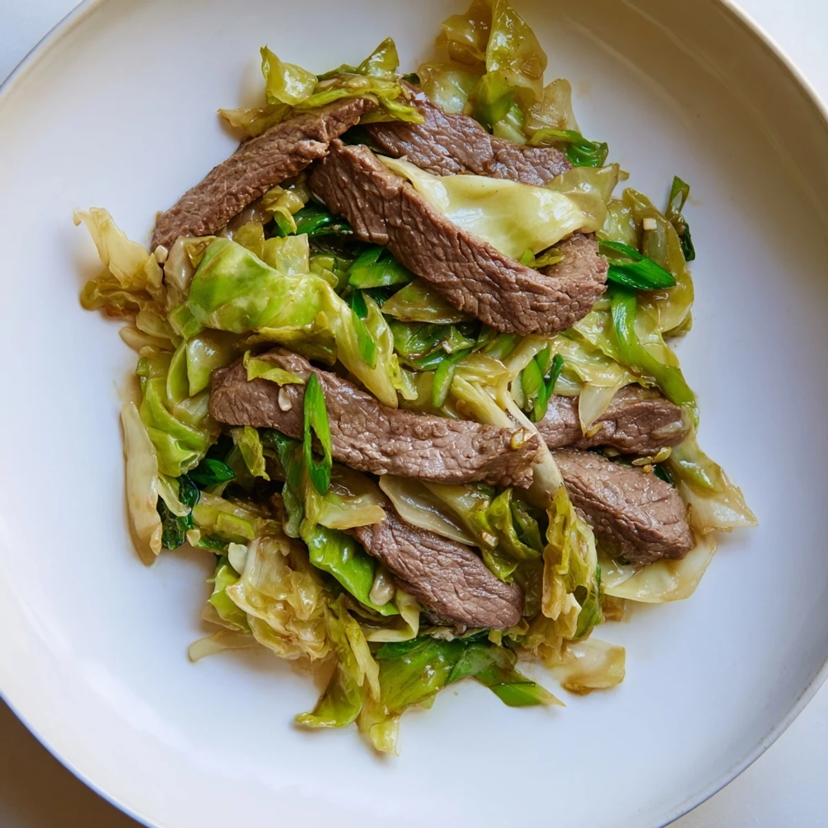 A close-up of Keto Friendly Beef and Cabbage Stir Fry plated with green onions and sesame seeds, perfect for a hearty weeknight dinner.