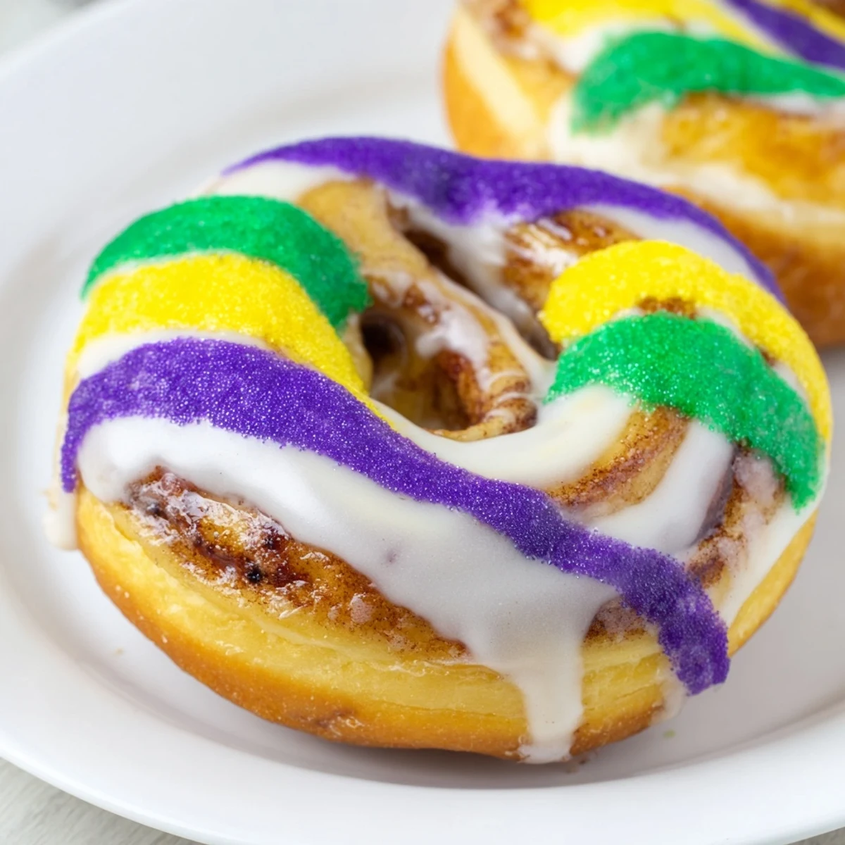 Glazed Mardi Gras King Cake Donuts with swirled cinnamon filling, dusted with festive colored sugars for celebration.