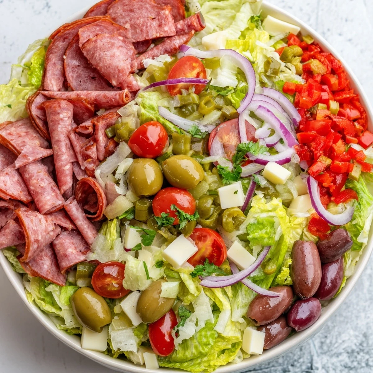 Hearty slices of Genoa salami and mortadella mingle with tangy olives and creamy provolone in this authentic New Orleans Muffuletta Salad served on greens.