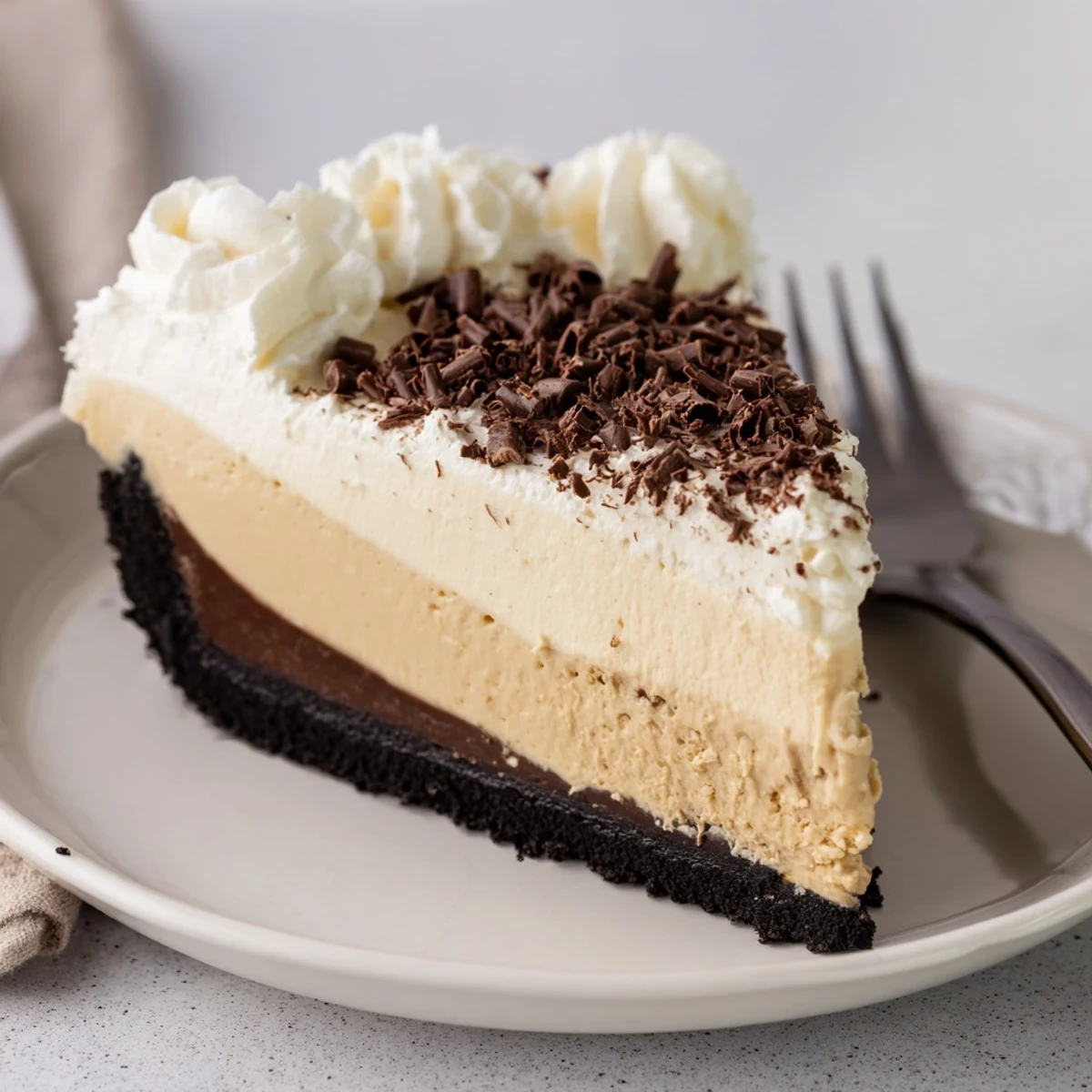 Close-up view of creamy Irish Cream Cheesecake with a chocolate cookie crust, featuring elegant swirls of cocoa-infused filling and a dusting of cocoa powder.