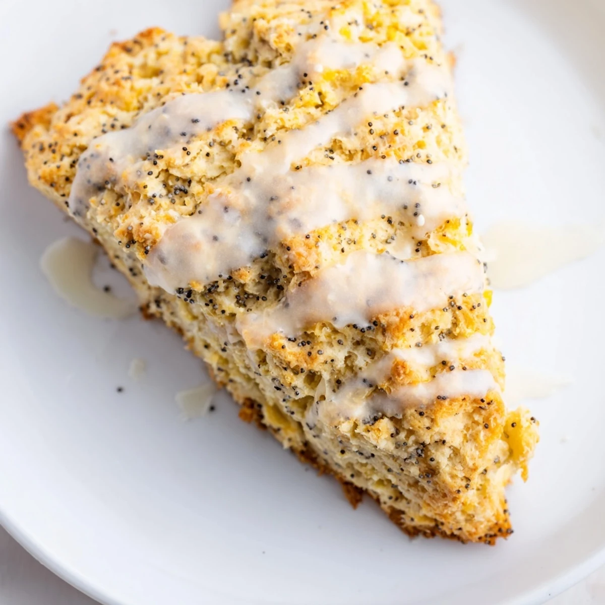 Overhead view of Lemon Poppy Seed Scones with a shiny glaze drizzle, accompanied by a cup of coffee and fresh lemon slices on the side.