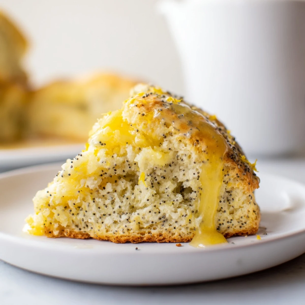 Freshly baked Lemon Poppy Seed Scones with a tangy lemon glaze, served warm with a cup of tea.
