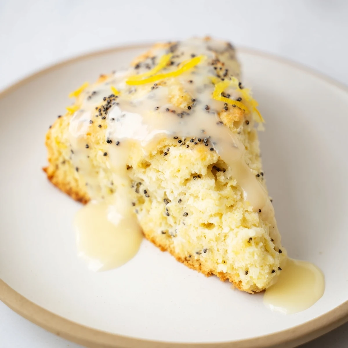 Freshly baked Lemon Poppy Seed Scones drizzled with sweet lemon glaze on a rustic wooden table.