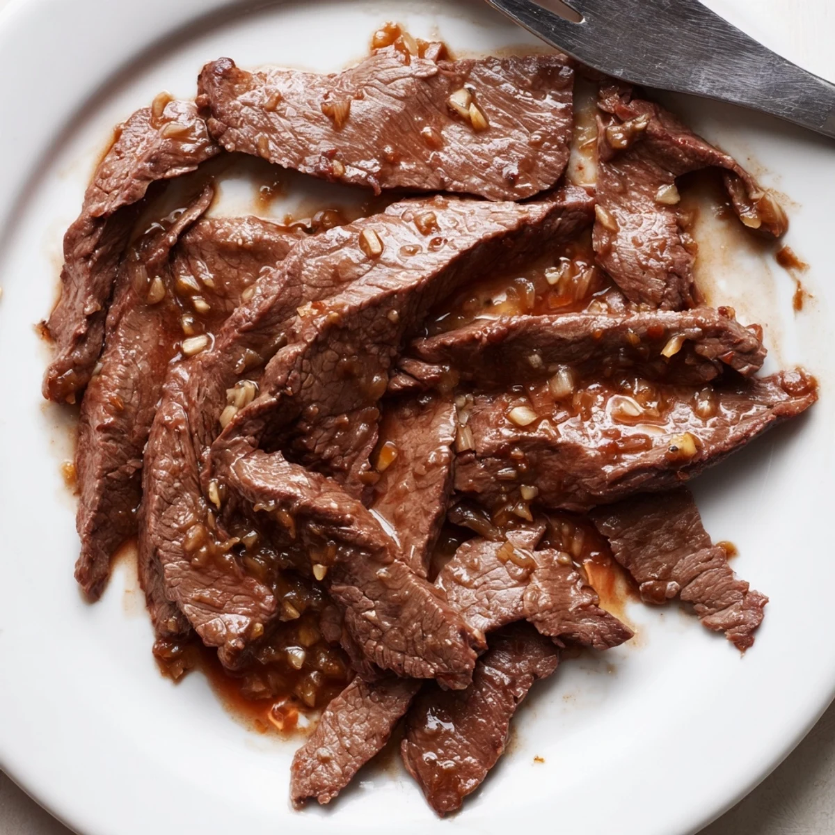 Enjoy Ultimate Slow Cooker Mongolian Beef served hot, garnished with sesame seeds and green onions, alongside crisp vegetables for a complete meal.
