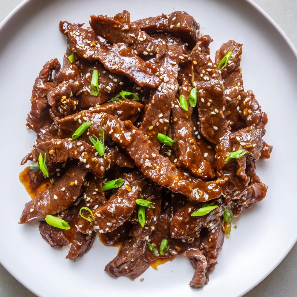 Steaming Ultimate Slow Cooker Mongolian Beef with tender beef strips and green onions over jasmine rice.