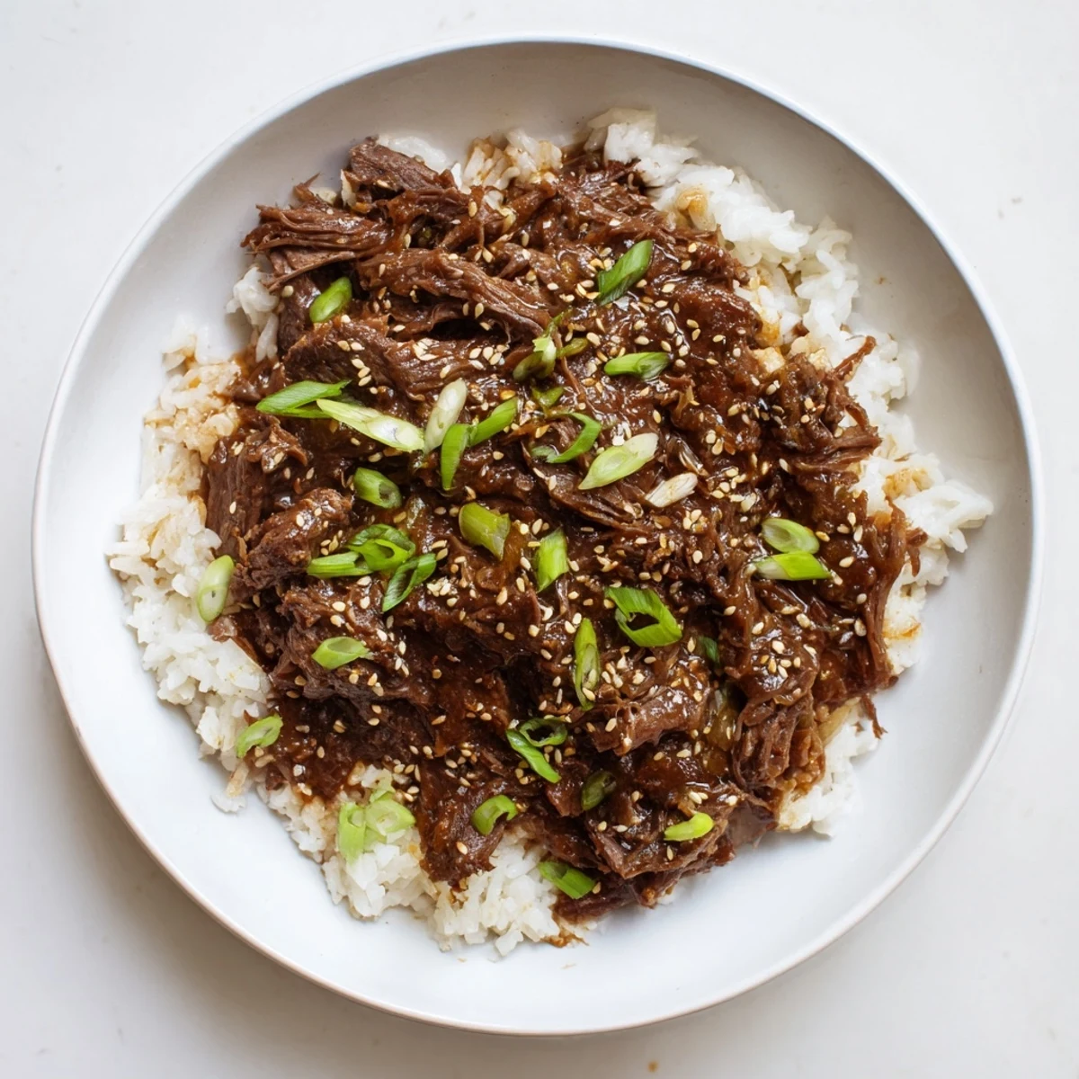 Tender shredded Crock Pot Korean Beef topped with green onions and sesame seeds.
