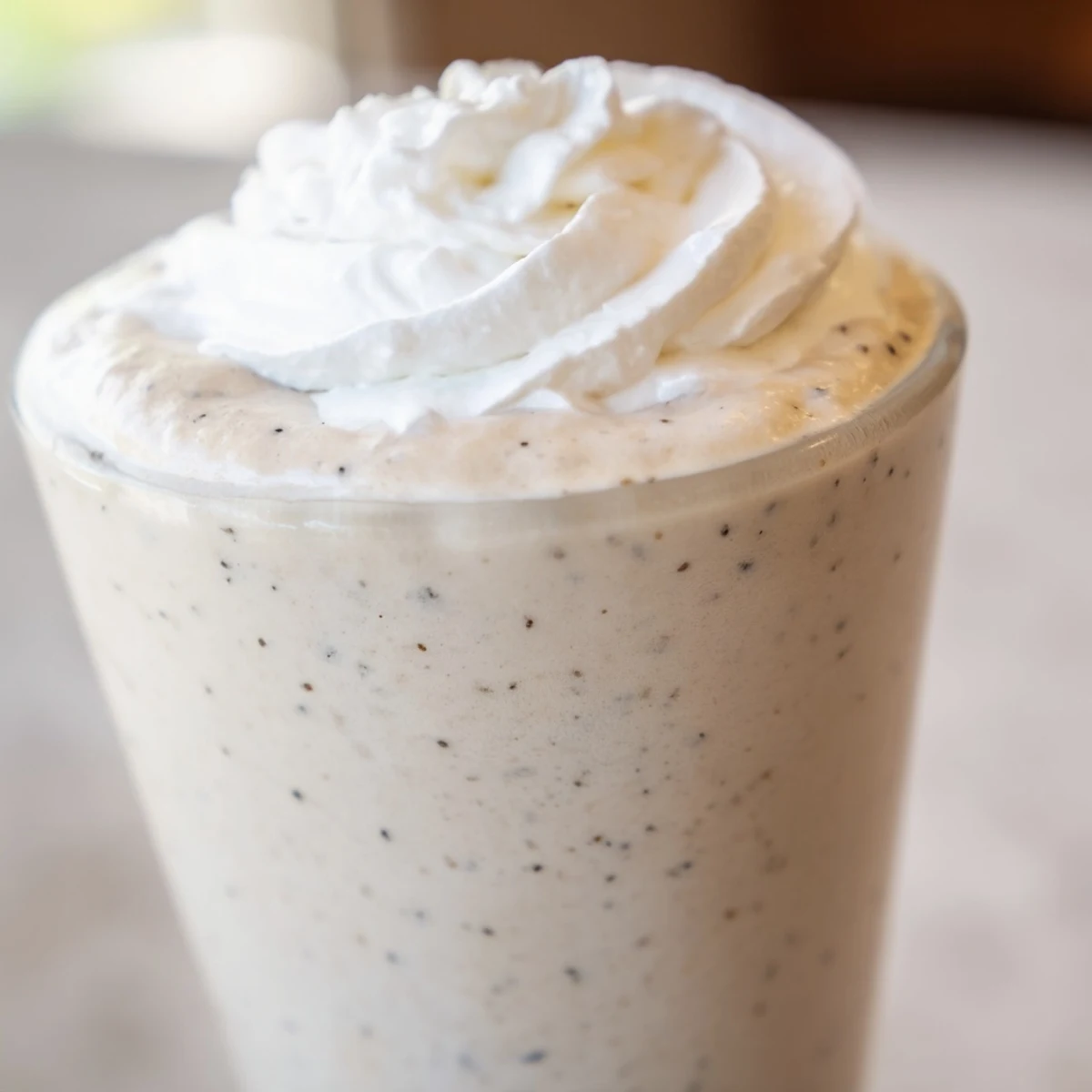 A creamy Starbucks Vanilla Bean Frappuccino topped with fluffy whipped cream in a tall glass.