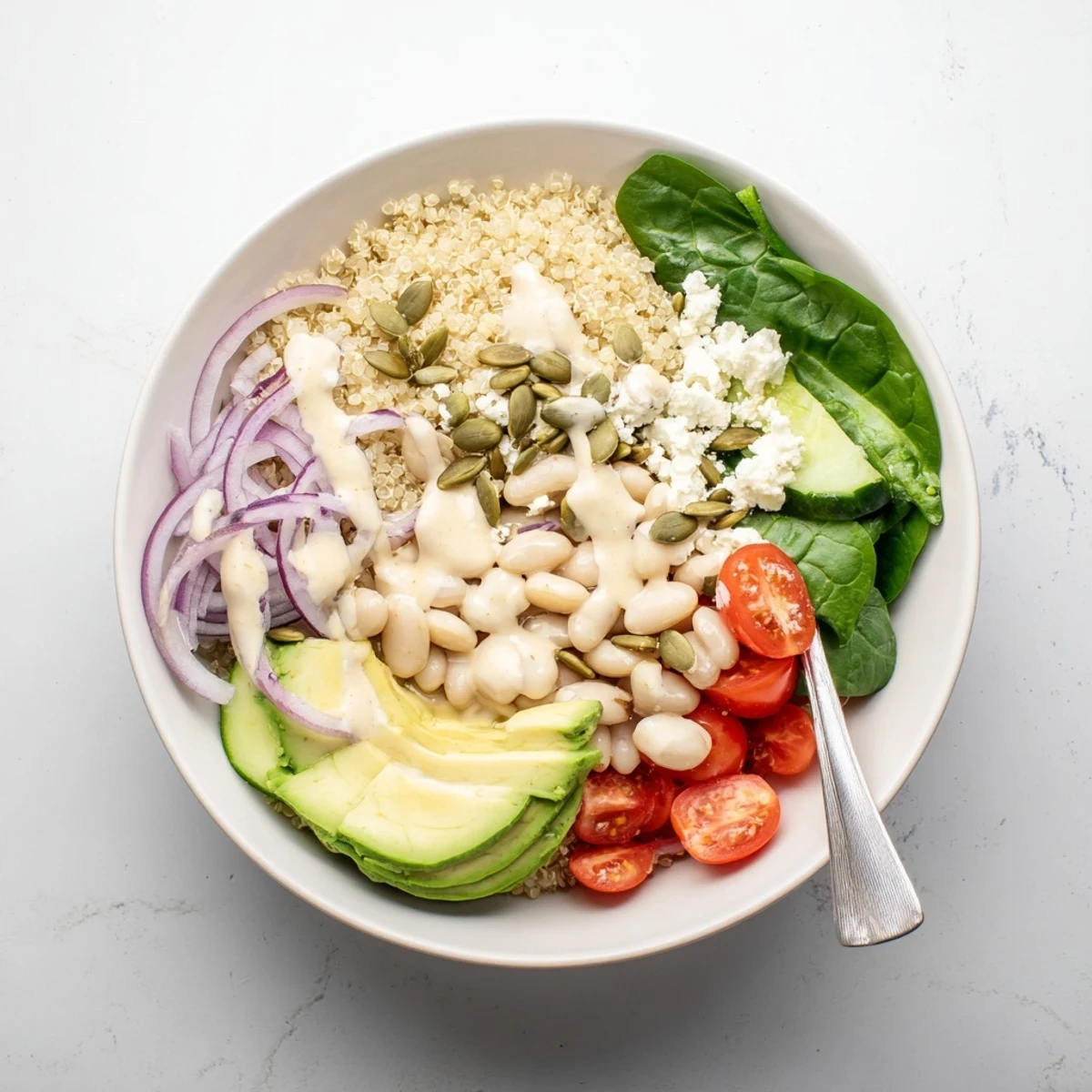A vibrant Spinach & White Bean Ultimate Protein Power Bowl showcases creamy avocado, white beans, and cherry tomatoes on fluffy quinoa.