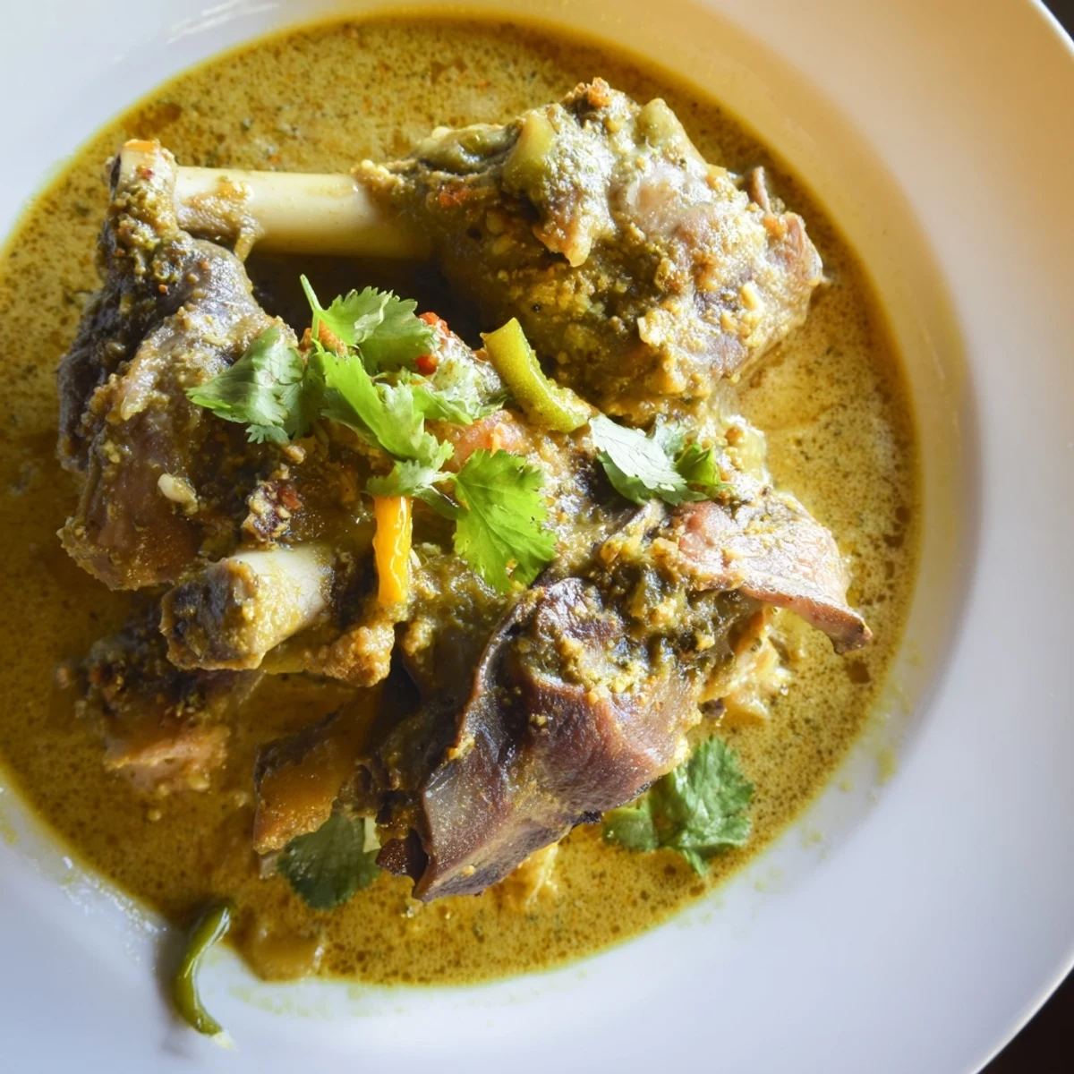 A close-up of Sri Lankan Lamb Shank Curry in a pot with coriander garnish.