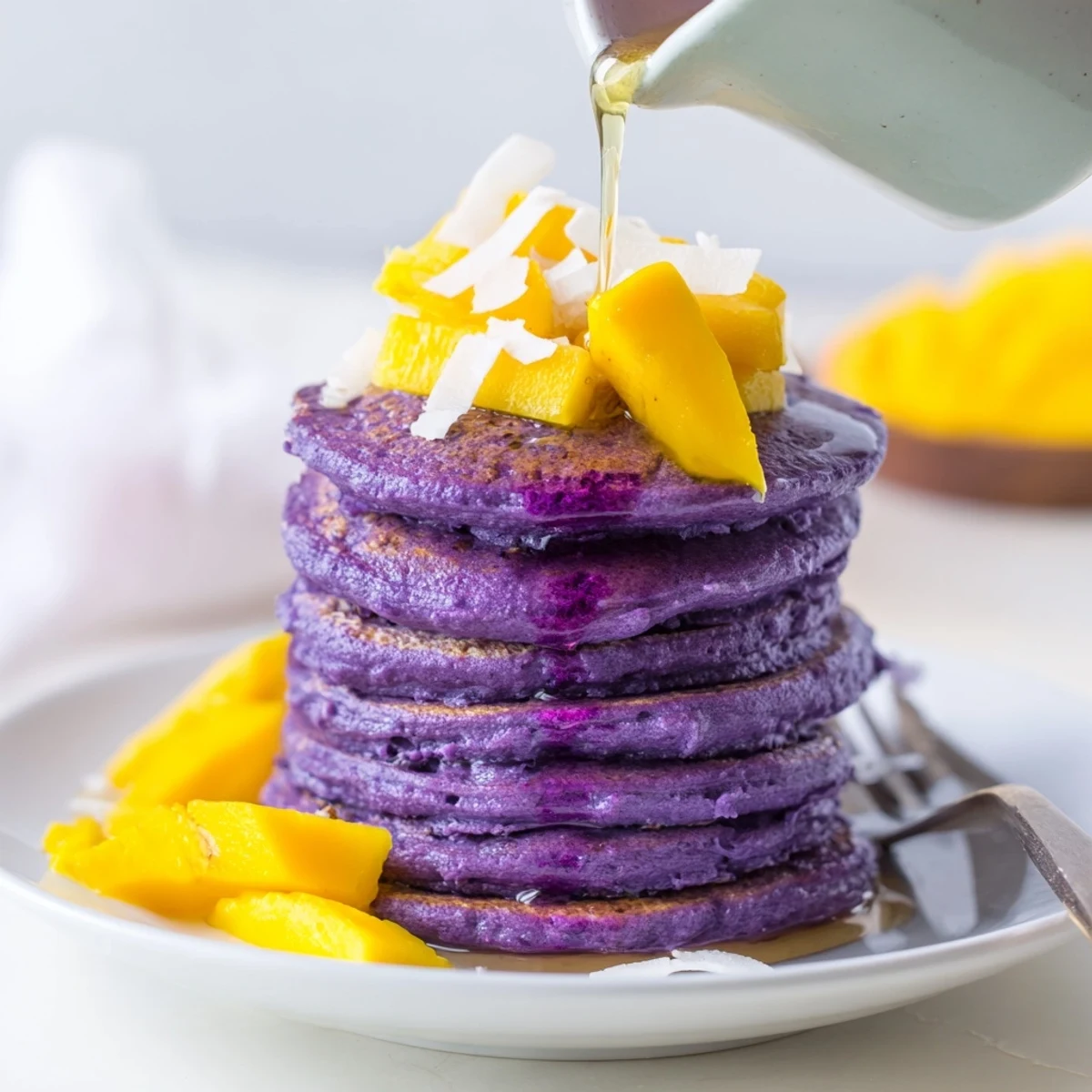 Warm Ube Mochi Pancakes stack high with a vibrant purple hue and chewy texture.