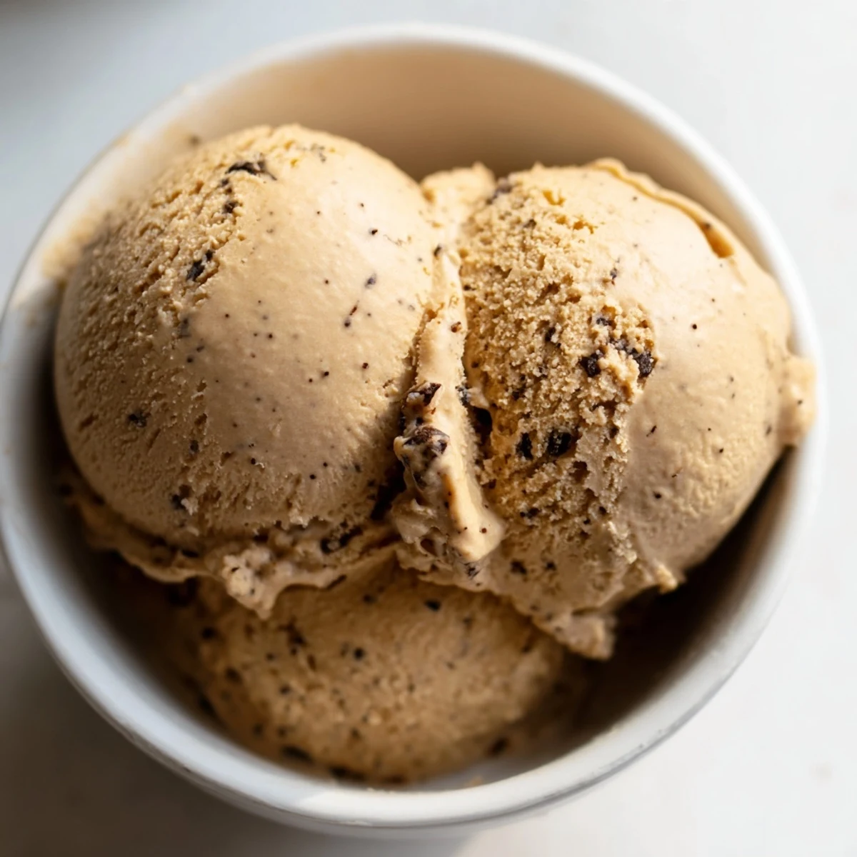 Close-up of Vietnamese Coffee Ice Cream beside hot espresso, perfect for affogato, highlighting rich coffee and condensed milk swirls.