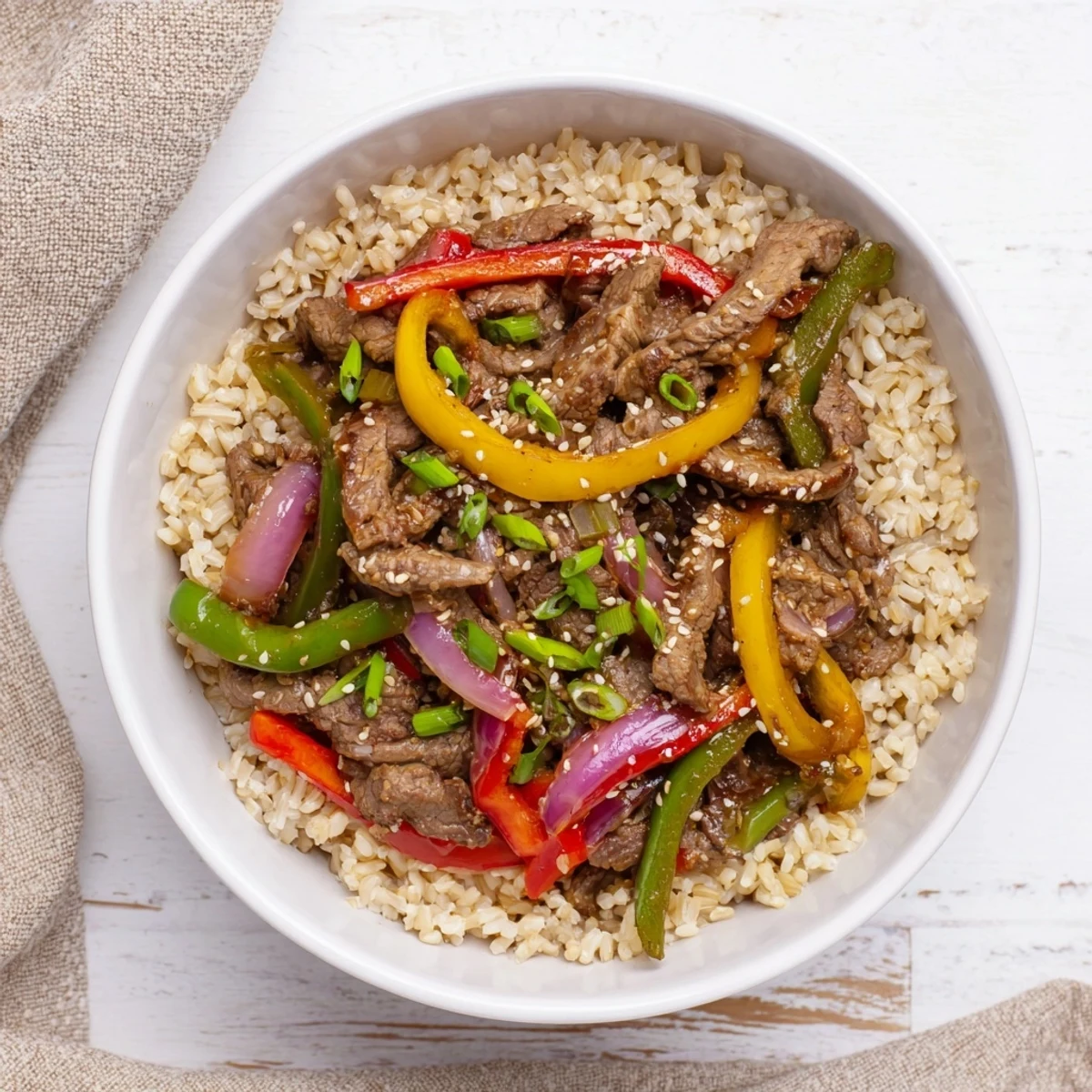 Garnished beef and pepper rice bowl featuring savory garlic-ginger glazed meat over fluffy brown rice