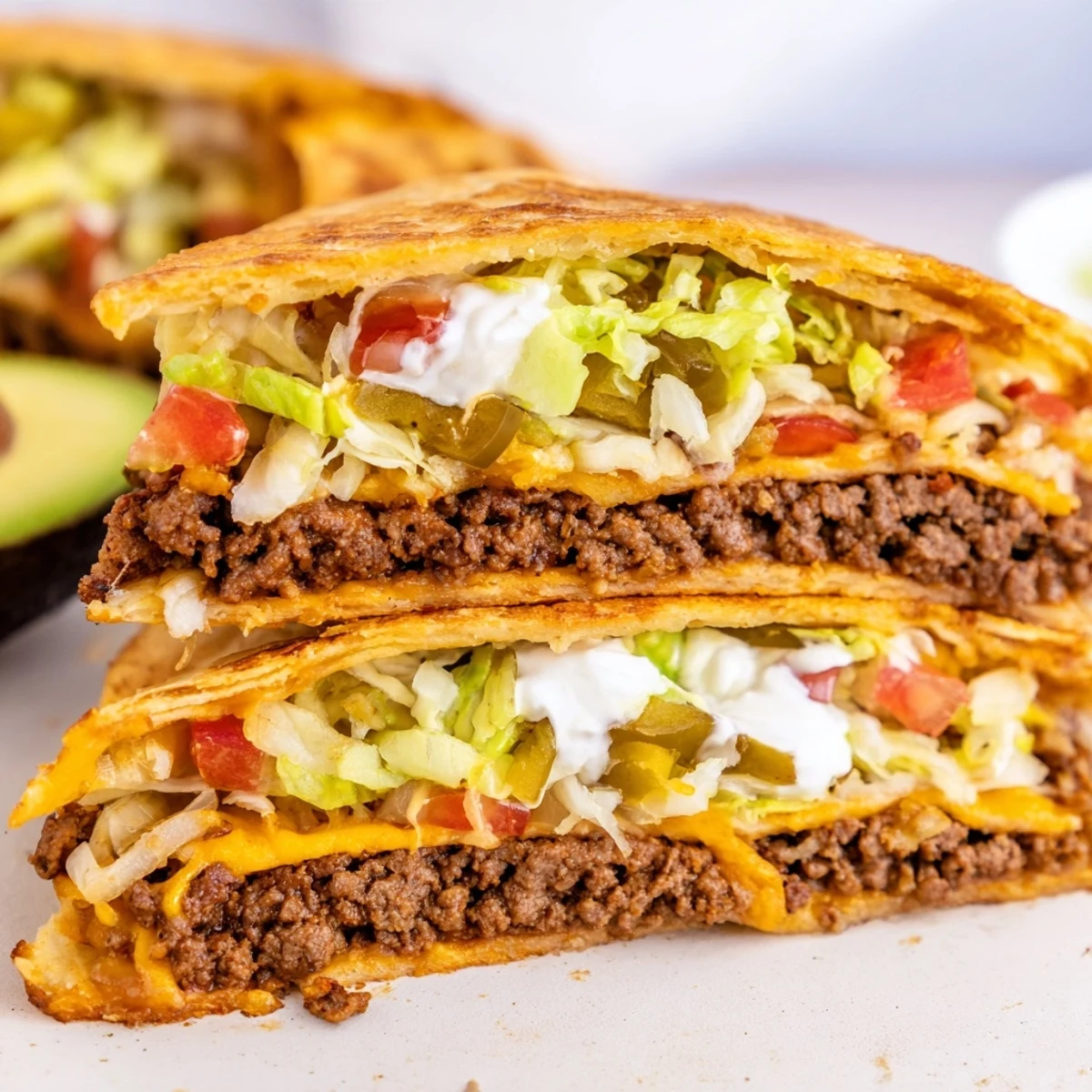 Golden keto crunchwrap sliced in half revealing seasoned beef, melted cheddar, and fresh colorful vegetable layers
