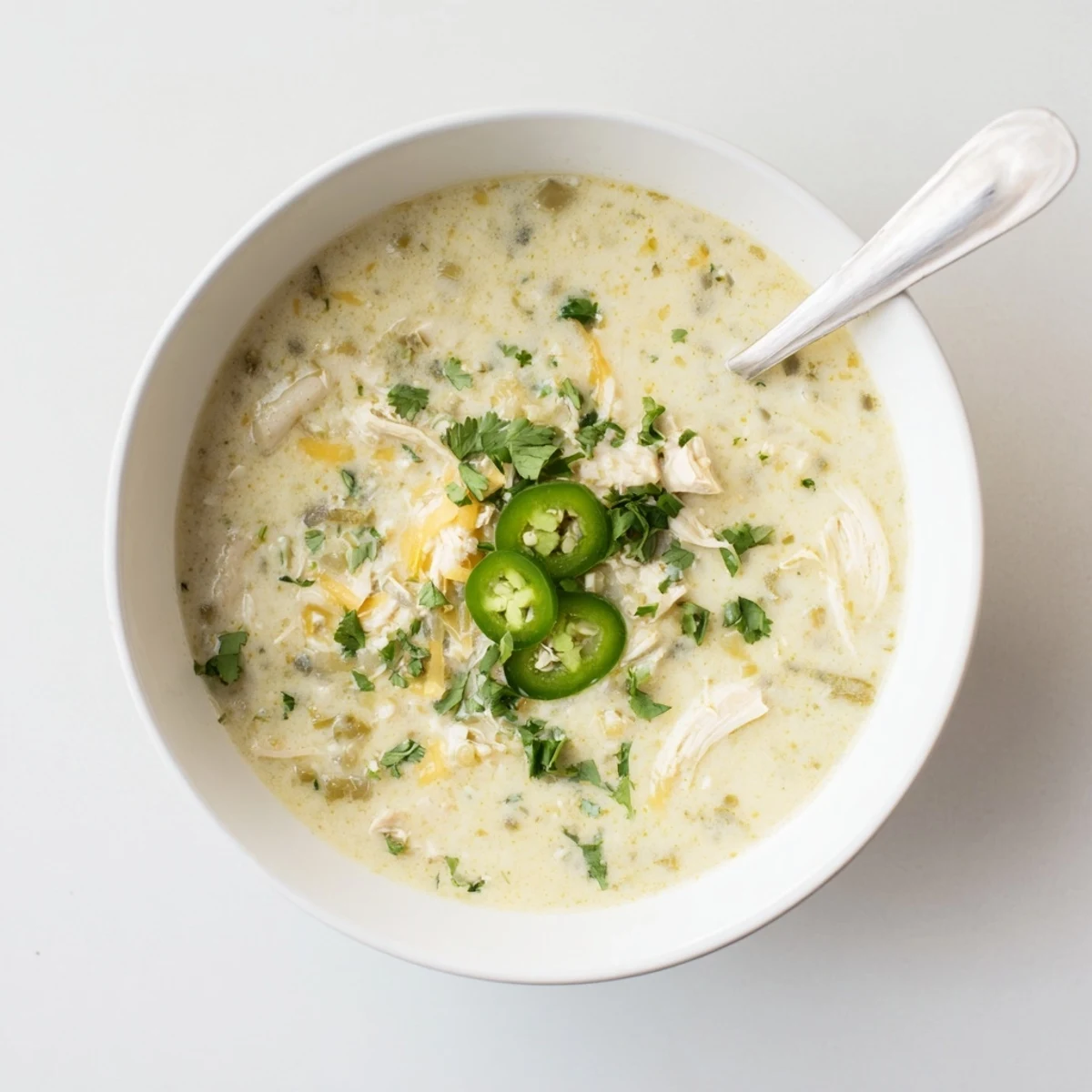 Simple keto white chicken chili simmering in a Dutch oven with melted cheese and tender shredded chicken