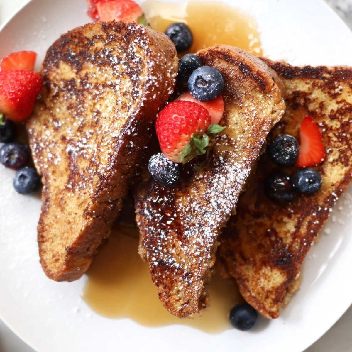 Crispy dairy-free French toast stacked high topped with colorful fresh fruit and sweet maple syrup