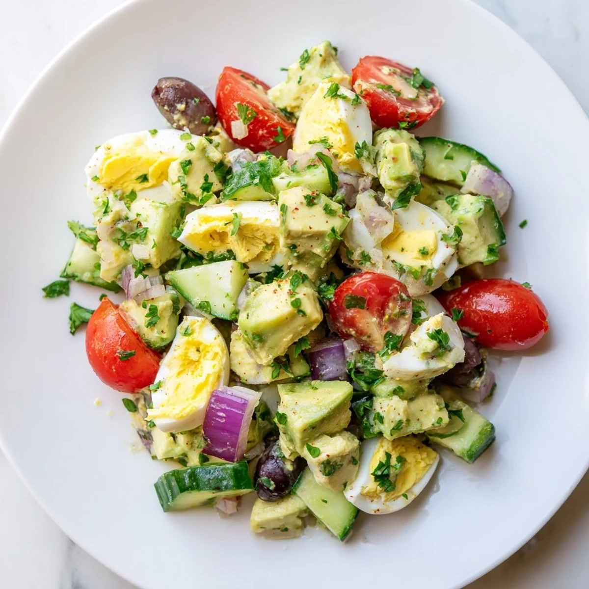 Vibrant bowl of zesty Mediterranean avocado egg salad featuring diced eggs, ripe avocado, cucumber, and Kalamata olives
