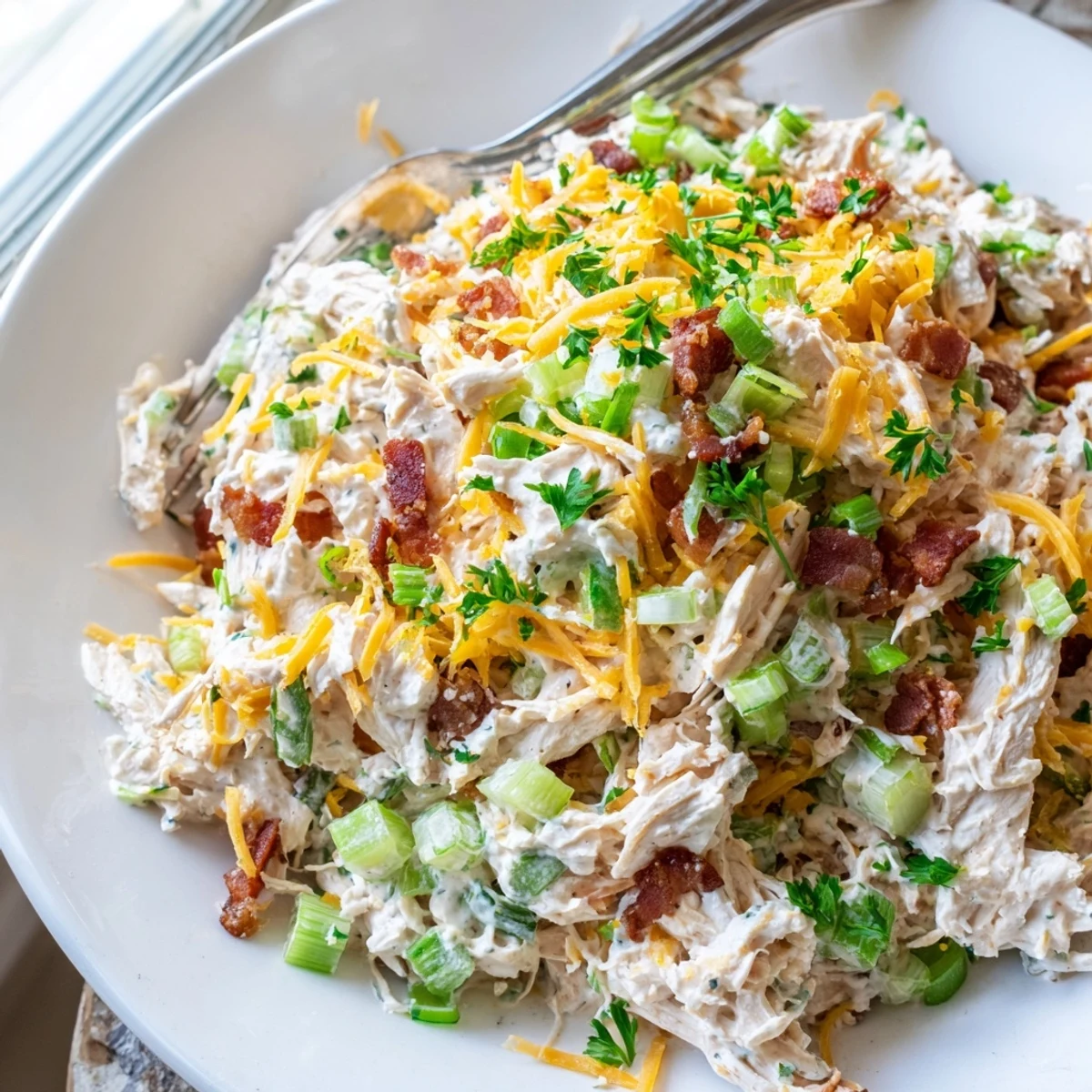 Creamy low carb jalapeno popper cottage cheese chicken salad topped with crispy bacon and fresh diced jalapeños in a white bowl