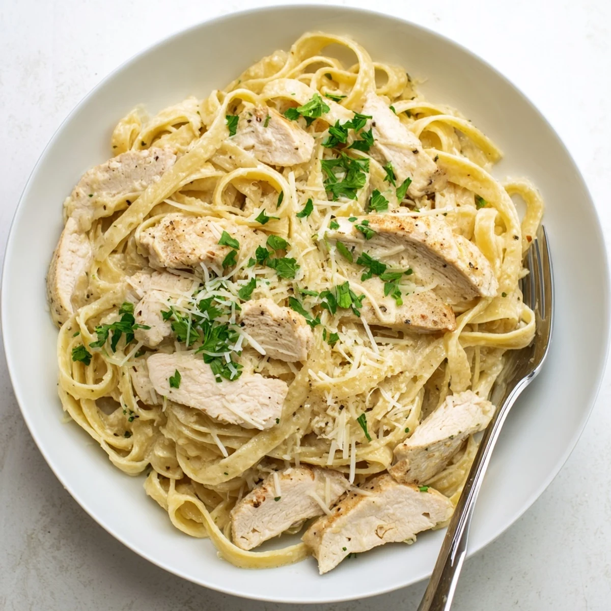Creamy garlic parmesan chicken pasta tossed in a rich white cheese sauce with sliced chicken breast