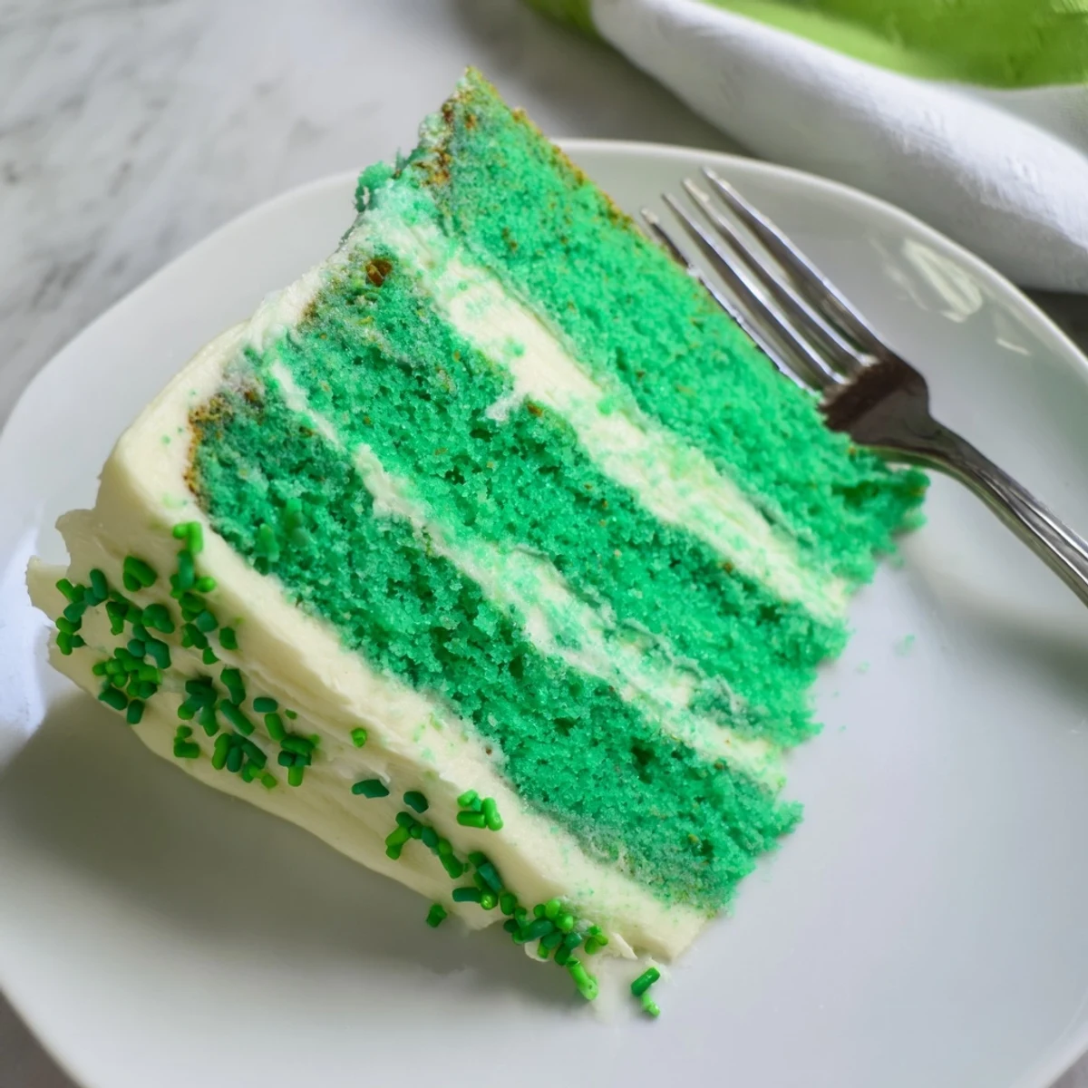 Homemade St. Patricks Day cake showcasing vibrant green layers topped with smooth vanilla icing