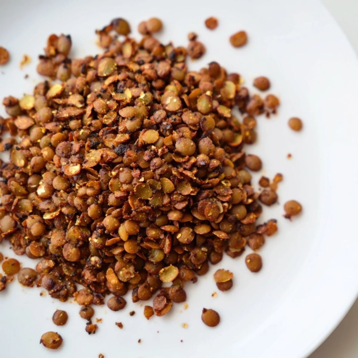 Bowl of seasoned crispy roasted lentils topped on fresh green salad with vegetables