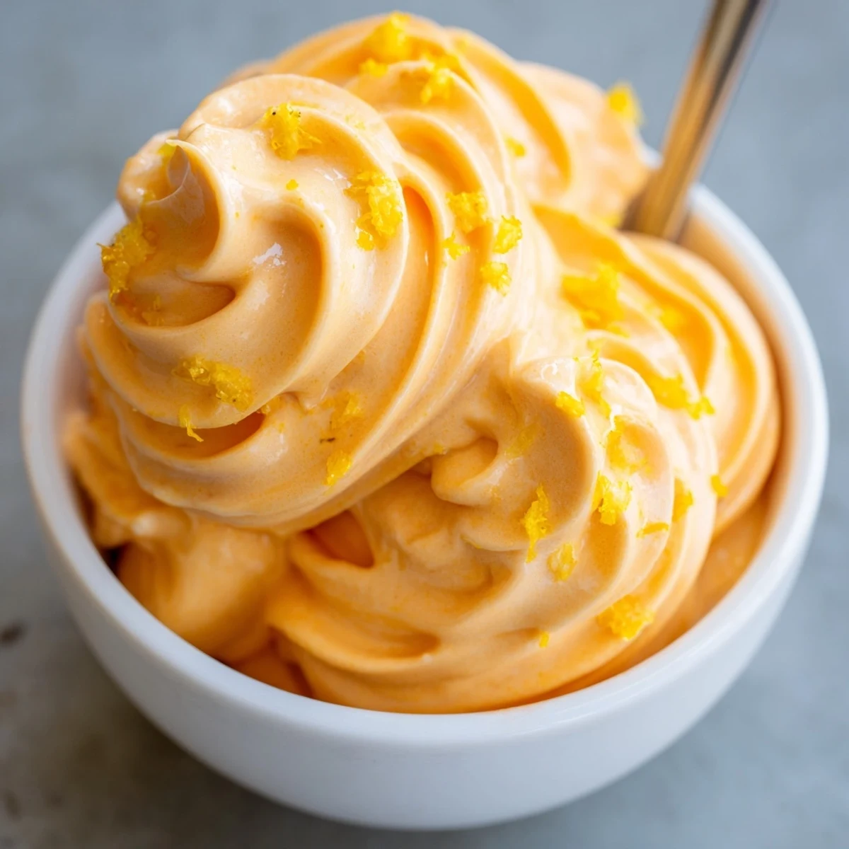 Refreshing frozen orange Dole Whip dessert piled high in a chilled glass bowl
