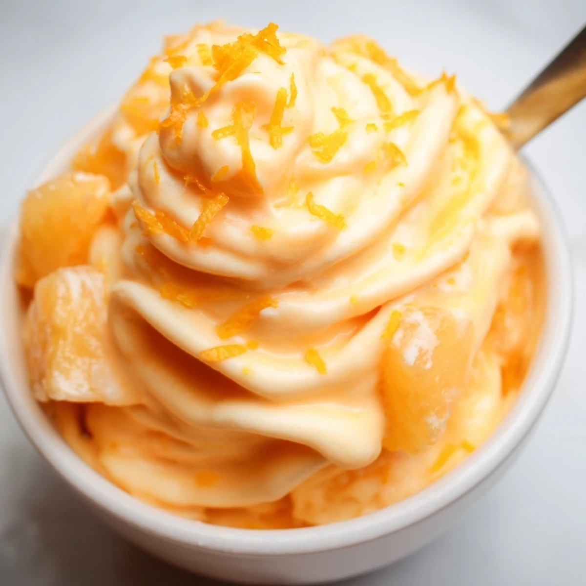 Creamy homemade orange Dole Whip served in a swirl with fresh orange zest garnish