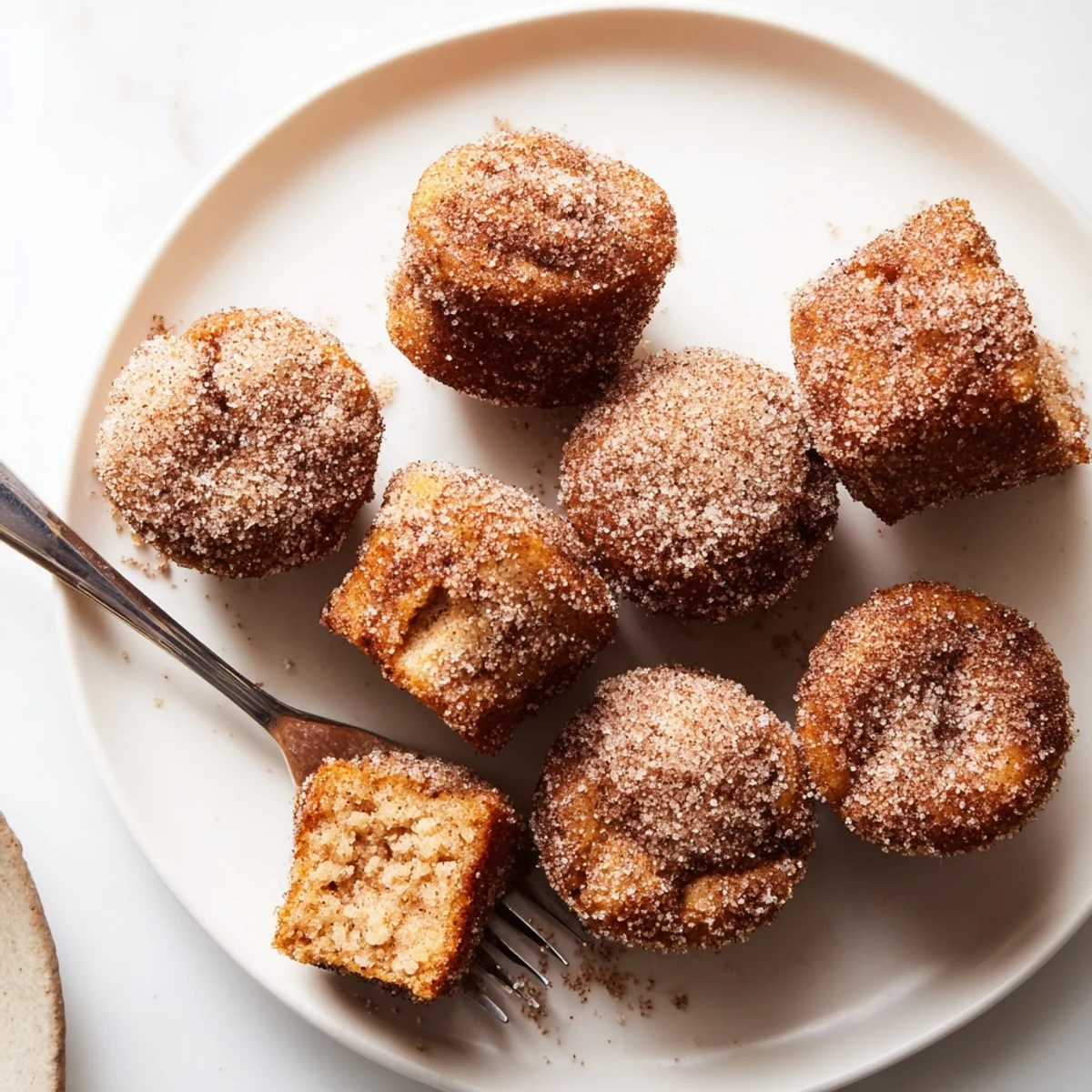 Freshly baked cinnamon sugar mini muffins with golden brown tops dusted in sweet spiced coating