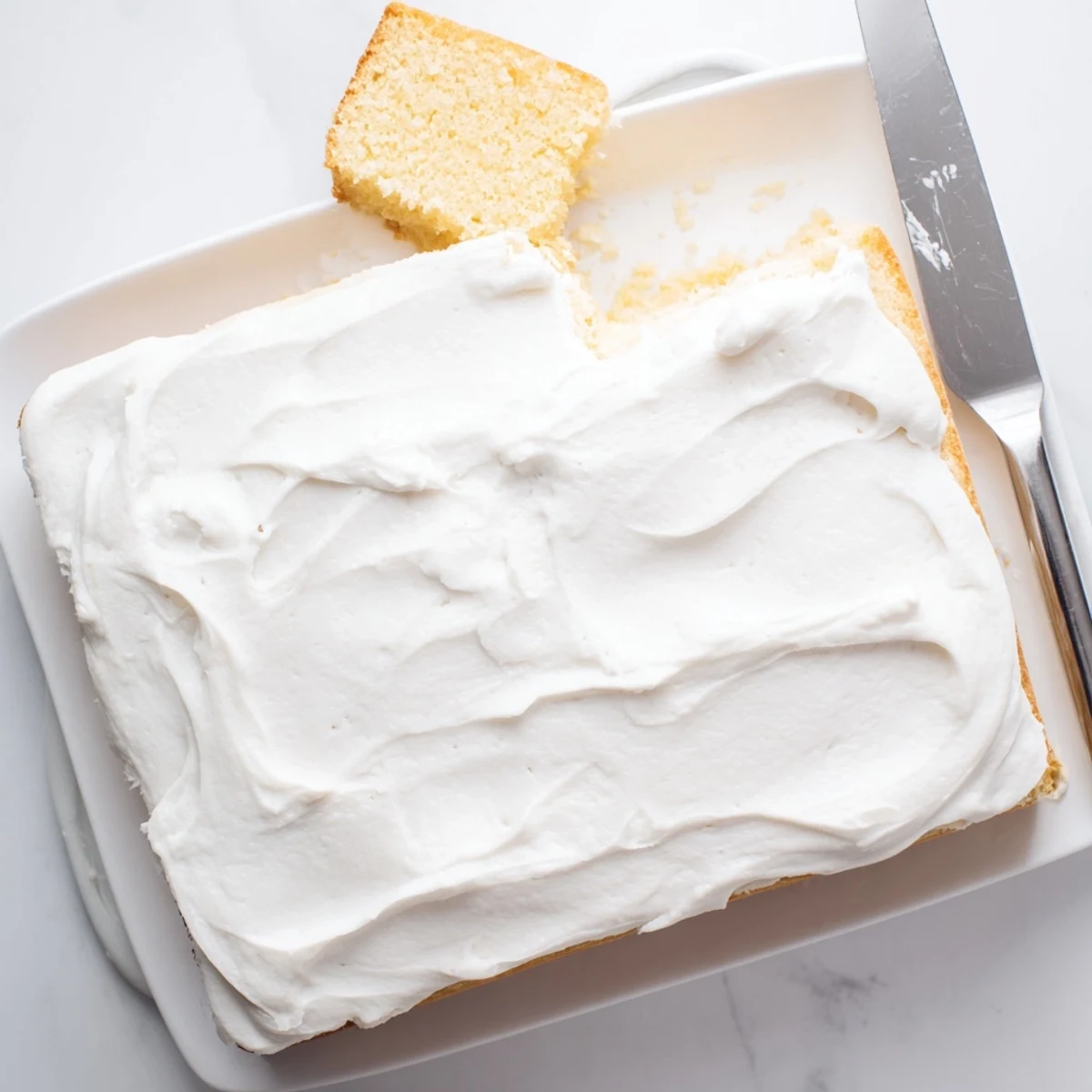 Golden vanilla Church Cake with fluffy white frosting dusted with powdered sugar on a decorative serving plate