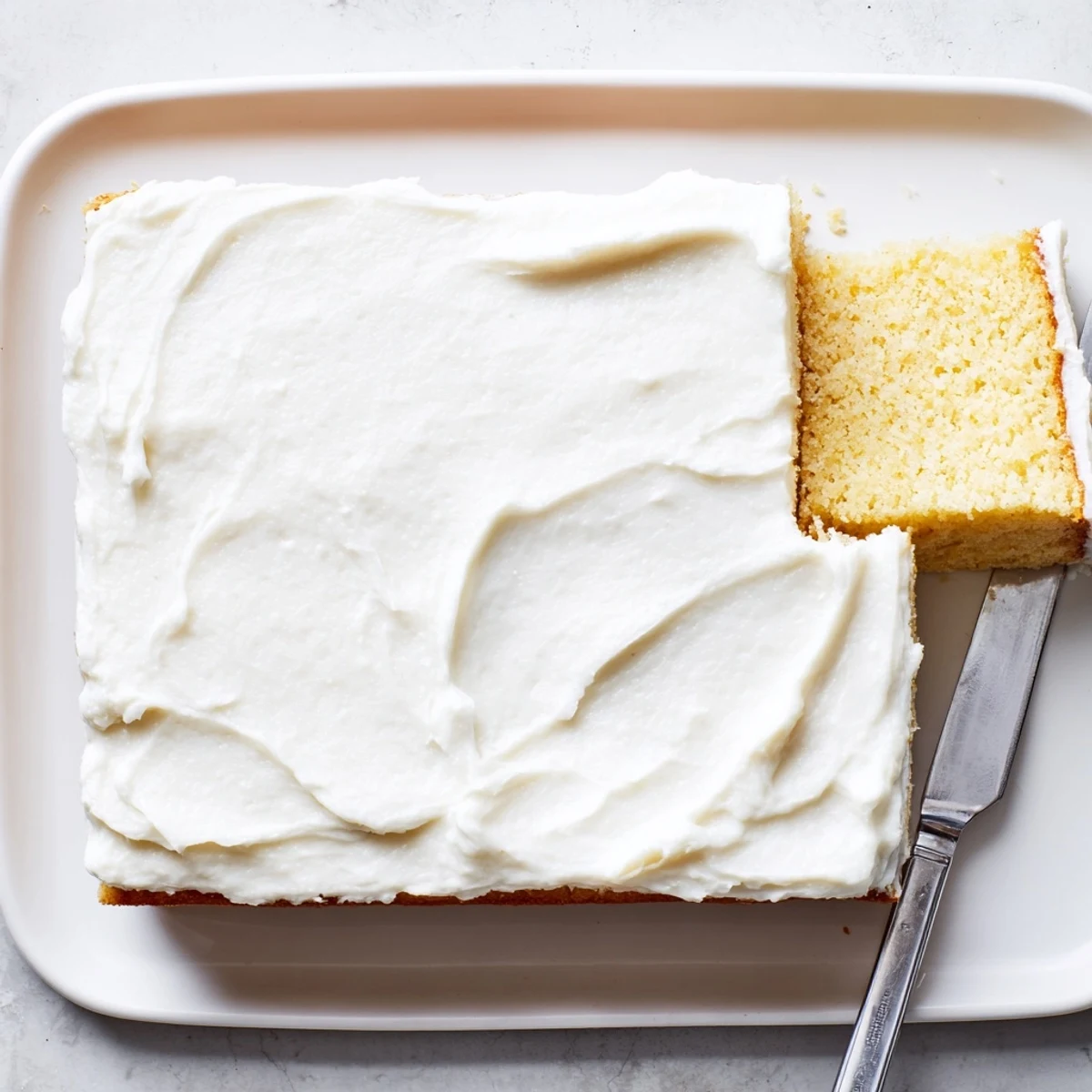 White frosted Church Cake sprinkled with coconut flakes displayed on a crystal cake stand for gatherings
