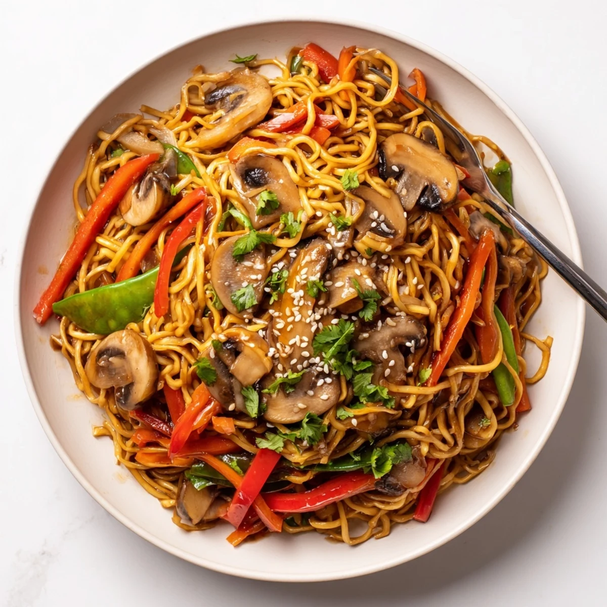 Wok-tossed noodles with sliced mushrooms bell peppers and snap peas coated in a rich Asian sauce