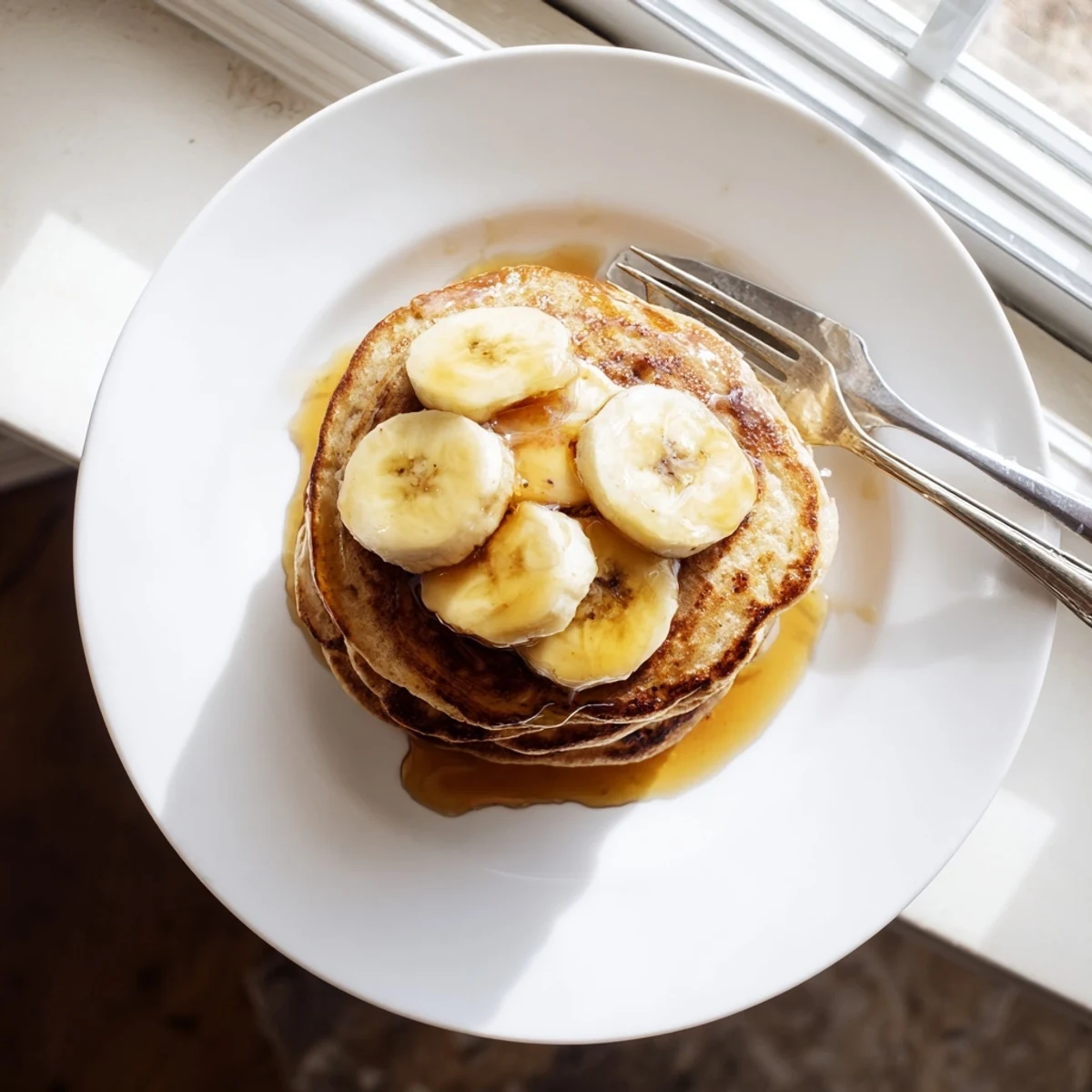 Protein-rich Greek yogurt banana pancakes cooking on a hot griddle with bubbles forming on the surface.