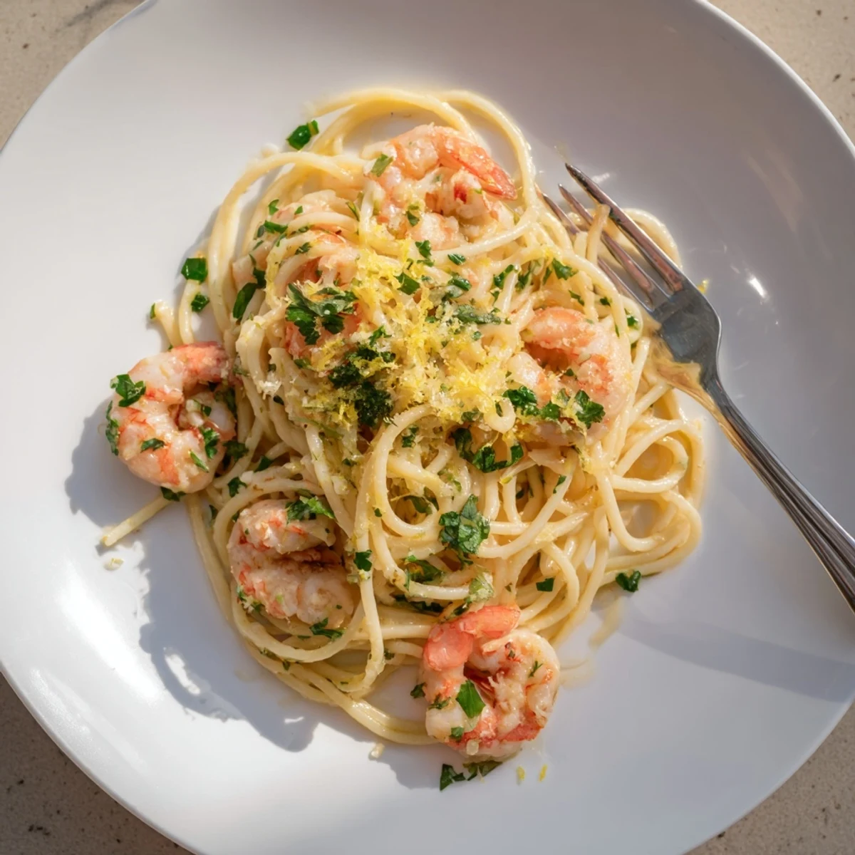 Golden shrimp scampi pasta glistening with garlic butter lemon sauce in a white bowl