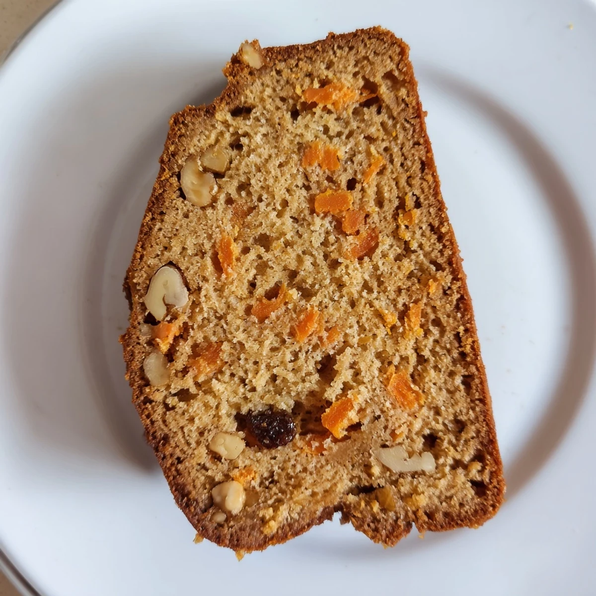 Golden brown carrot cake banana bread loaf with visible grated carrot specks and warming cinnamon spices
