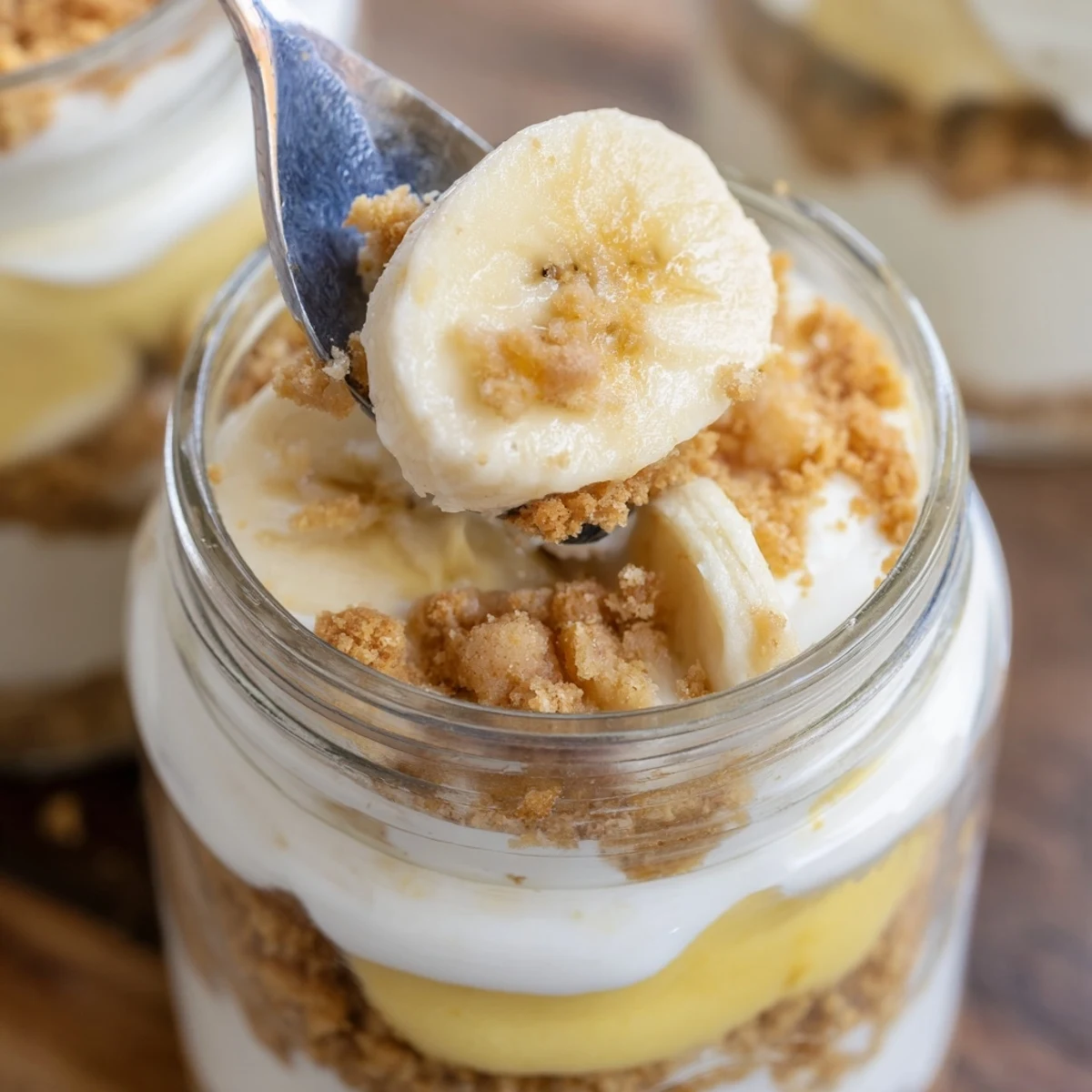Creamy no bake banana pudding cheesecake cups with fresh banana slices and vanilla wafer crumbs