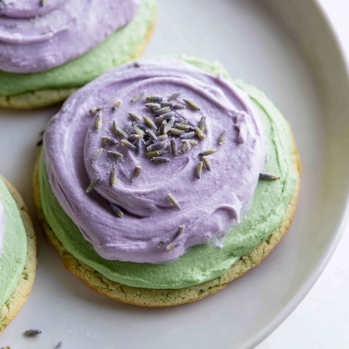 Matcha sugar cookies with lavender frosting arranged on a rustic white serving plate