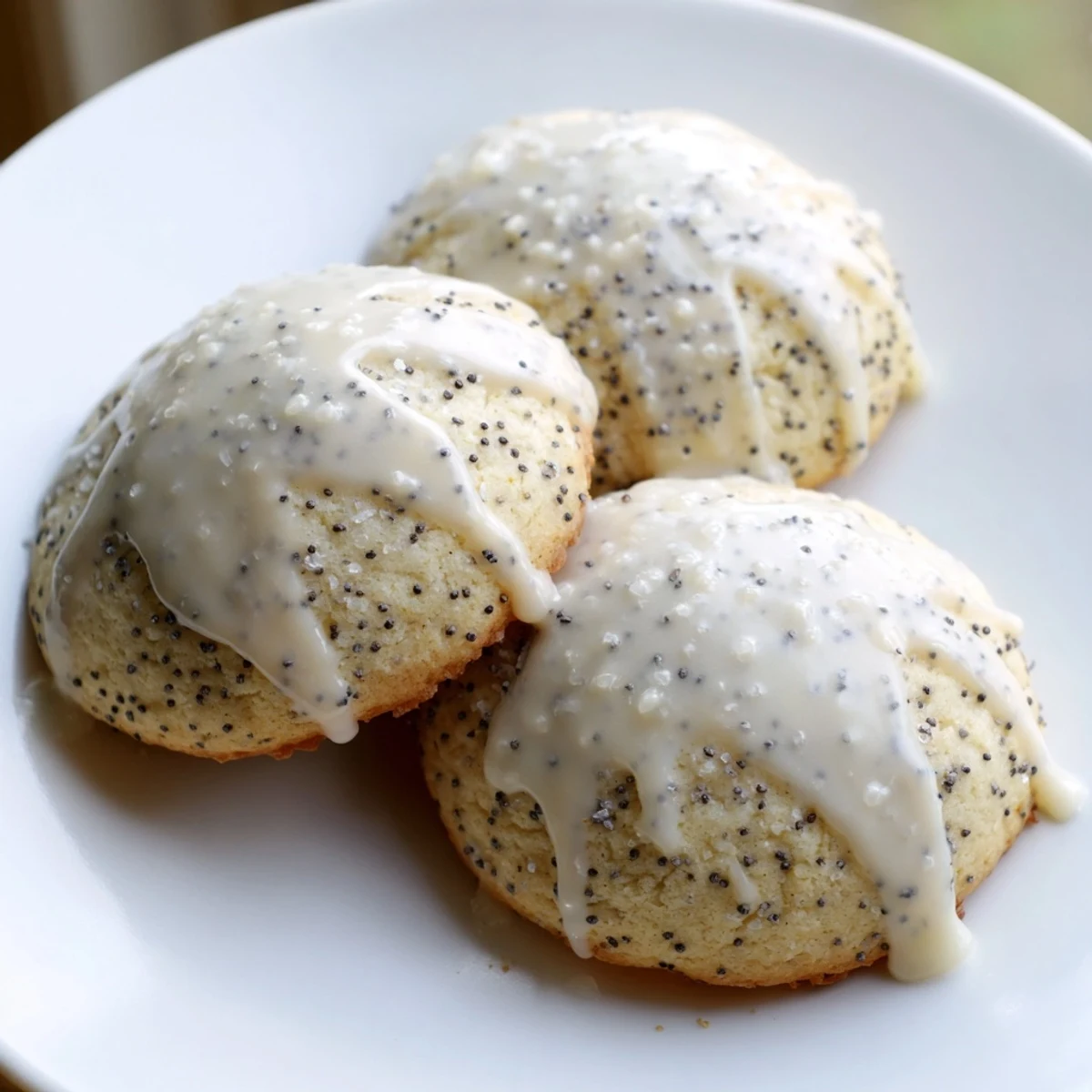 Lemon poppy seed cookies with golden edges and bright citrus glaze on rustic white plate