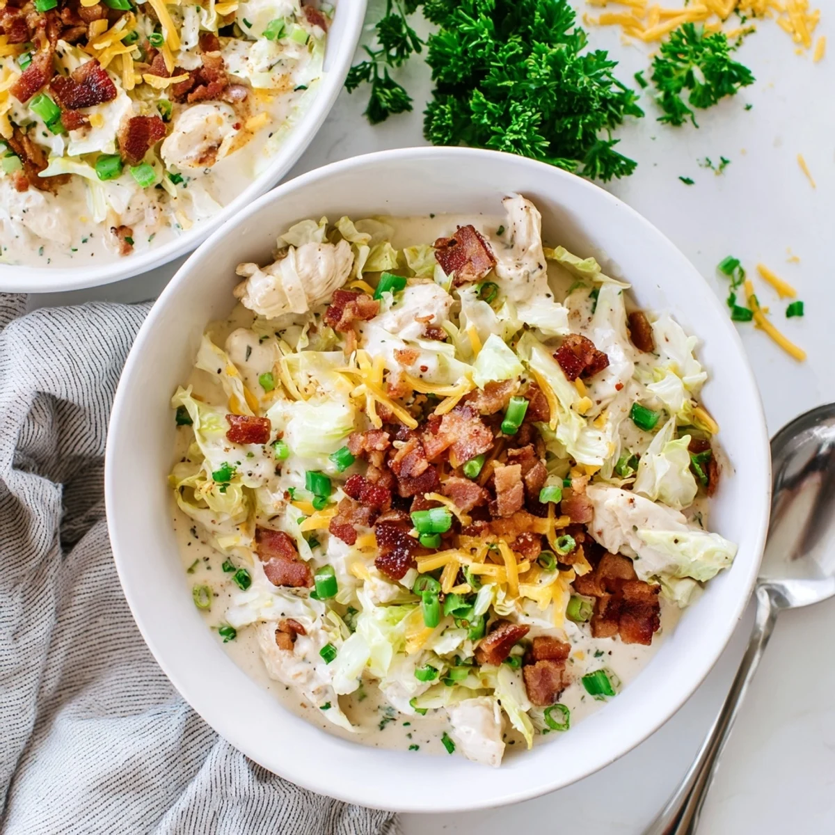 Creamy chicken bacon ranch cabbage bowls topped with crispy bacon and fresh parsley garnish