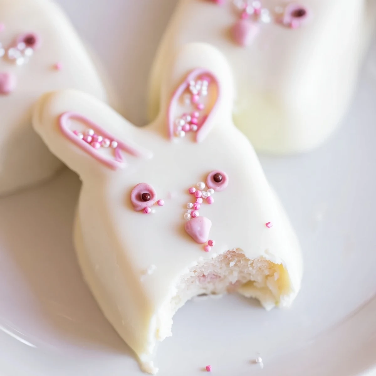 Adorable white chocolate bunny cakesicles with candy eyes on a festive Easter dessert tray