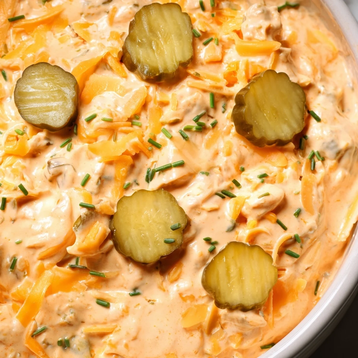 Tangy buffalo pickle dip topped with chopped chives and pickle slices ready for party snacking