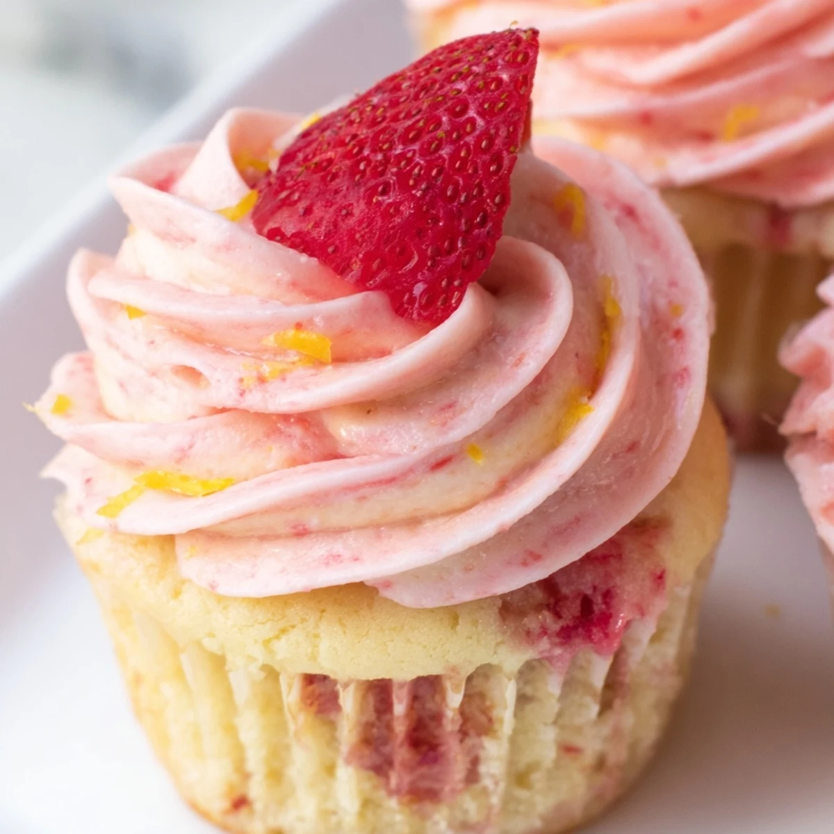 Pink frosted strawberry lemonade cupcakes topped with swirled buttercream on a rustic wooden serving board