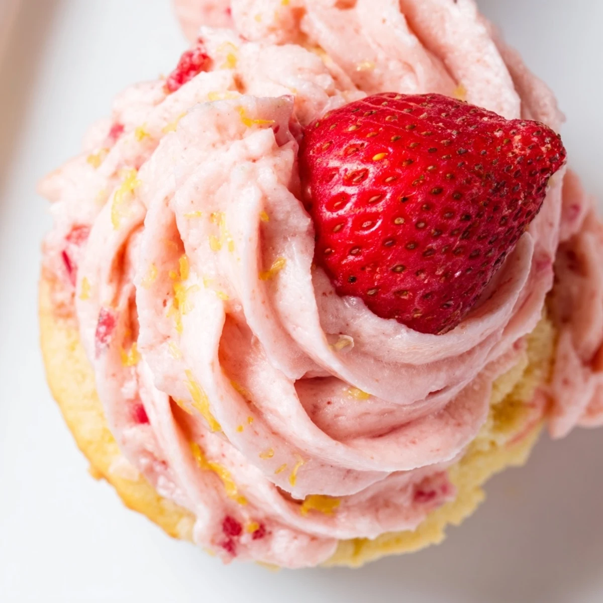 Fresh strawberry lemonade cupcakes with fluffy pink frosting piped high and garnished with lemon zest