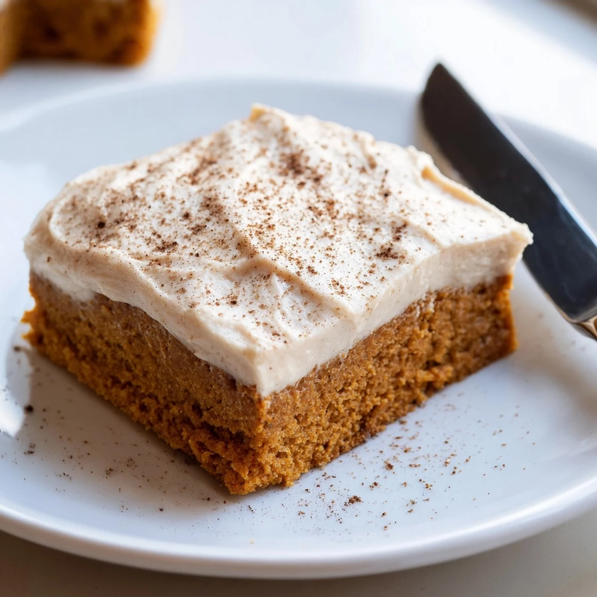 Warm spiced pumpkin bars with cream cheese frosting sliced on a rustic cutting board