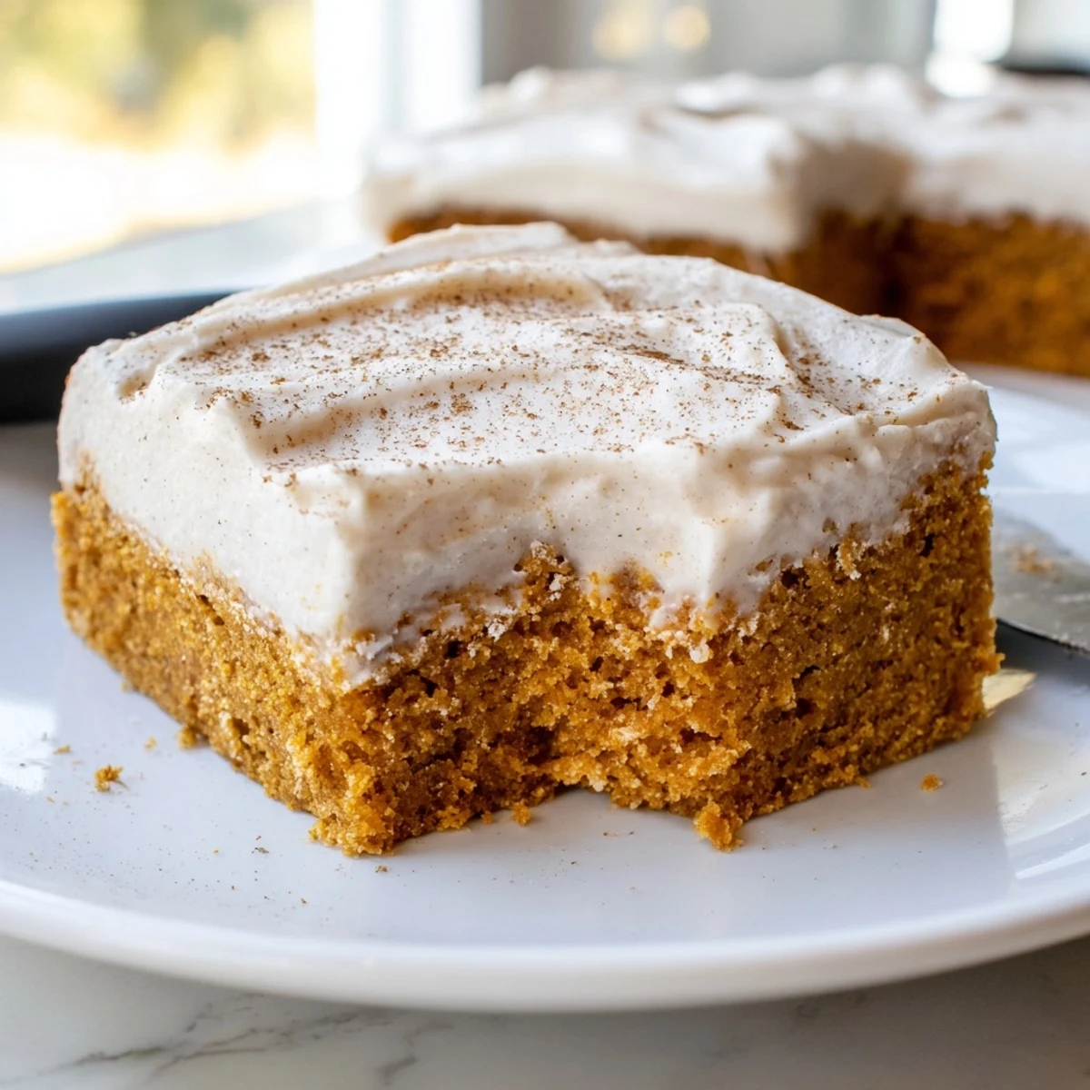 Thick pillowy cream cheese frosting spread over golden spiced pumpkin bars with fall spices