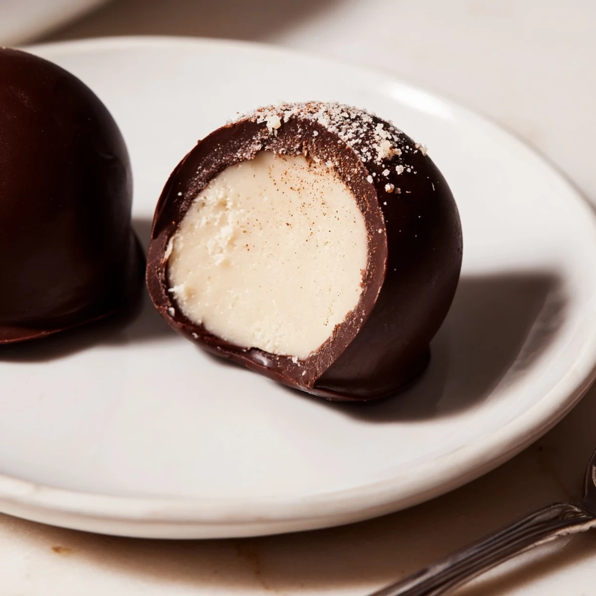 A bite-sized plate of Dark Chocolate Eggnog Truffles beside festive napkins, creamy centers