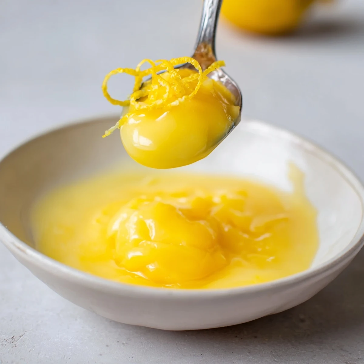Jar of Lemon Curd Recipe cooling beside whisk, zesty yellow and smooth