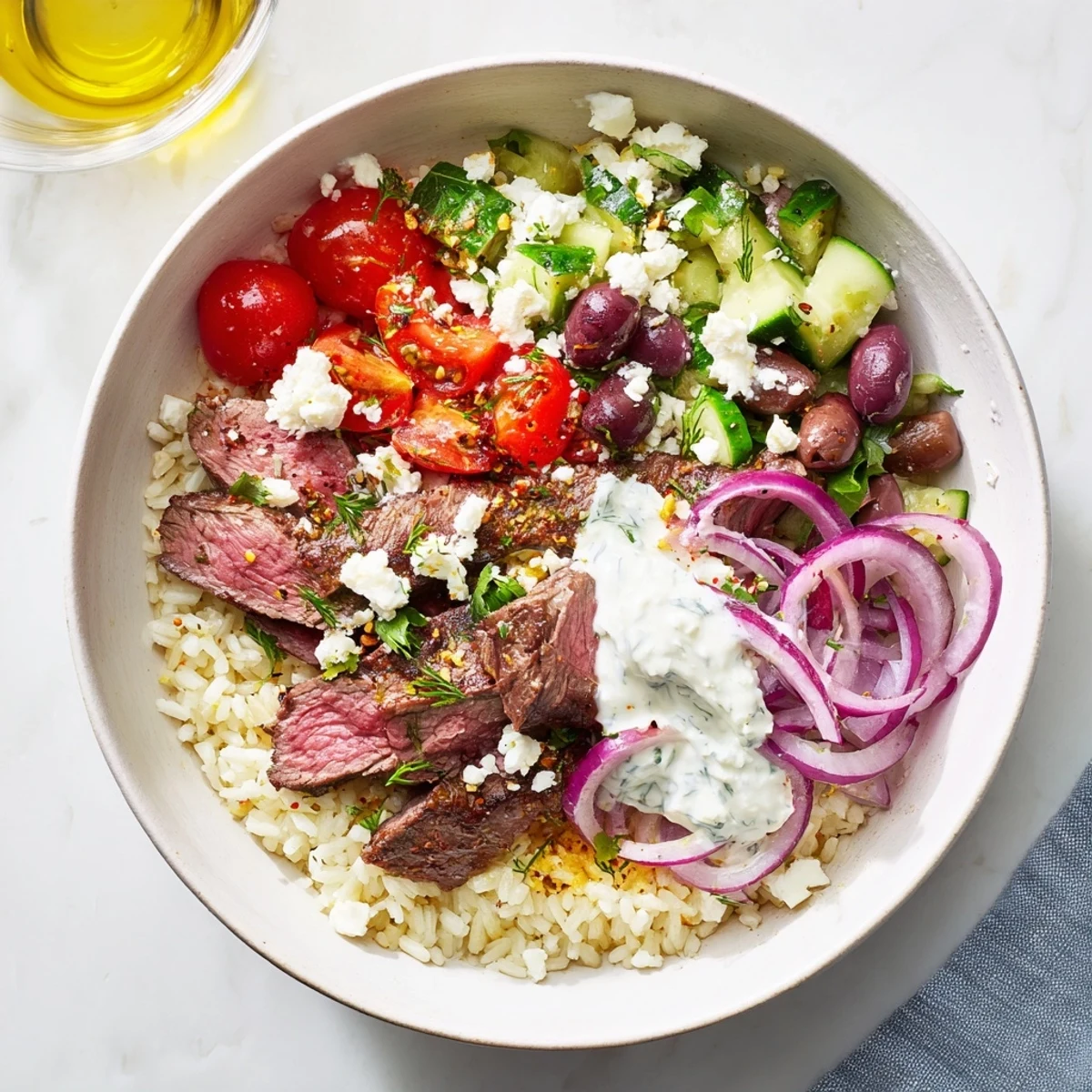 Colorful Mediterranean steak bowl featuring marinated sirloin, cherry tomatoes, cucumber, and crumbled feta