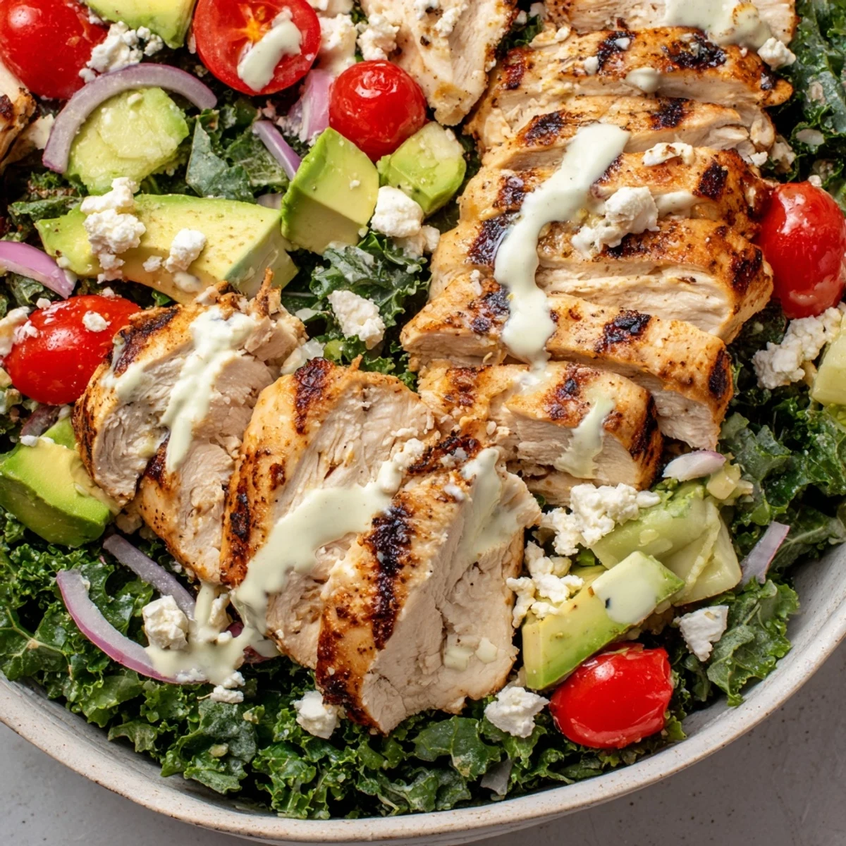 Colorful marinated kale and chicken bowls topped with fresh vegetables and zesty dressing