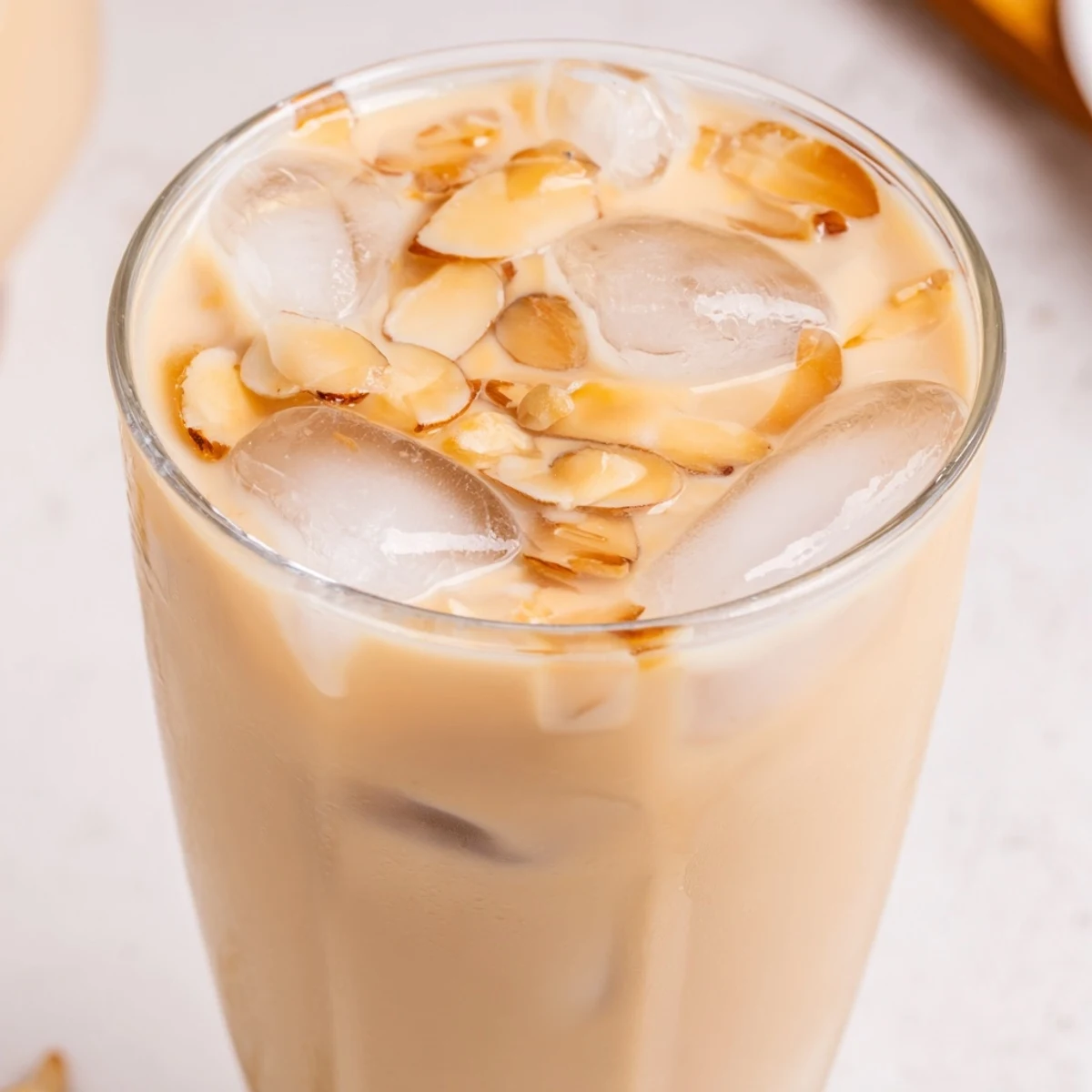 Chilled glass of refreshing summer roasted almond milk drink topped with cream and ice